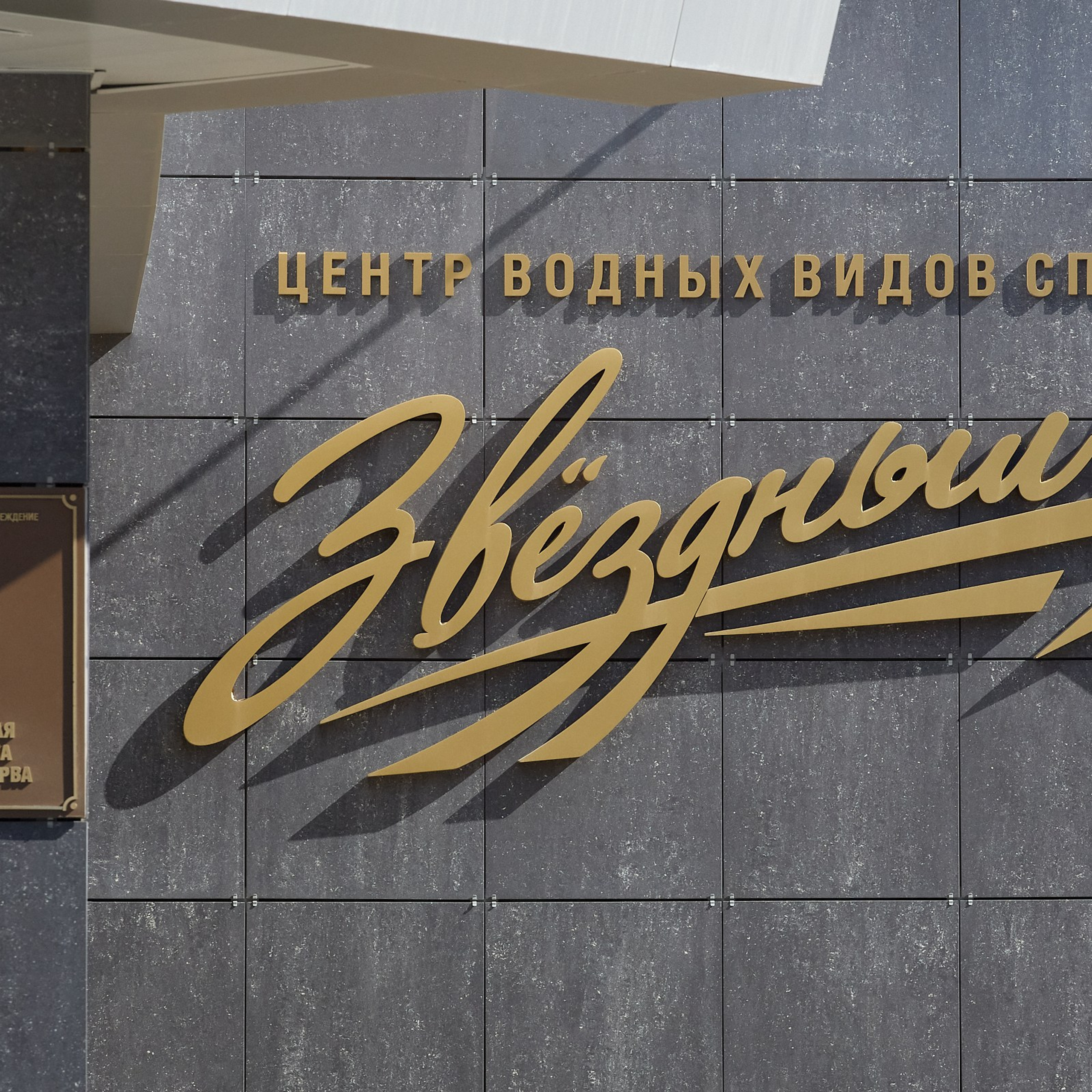 Большие жёлтые буквы  названия и табличка на входе, элементы бренд-айдентики бассейна «Звёздный».