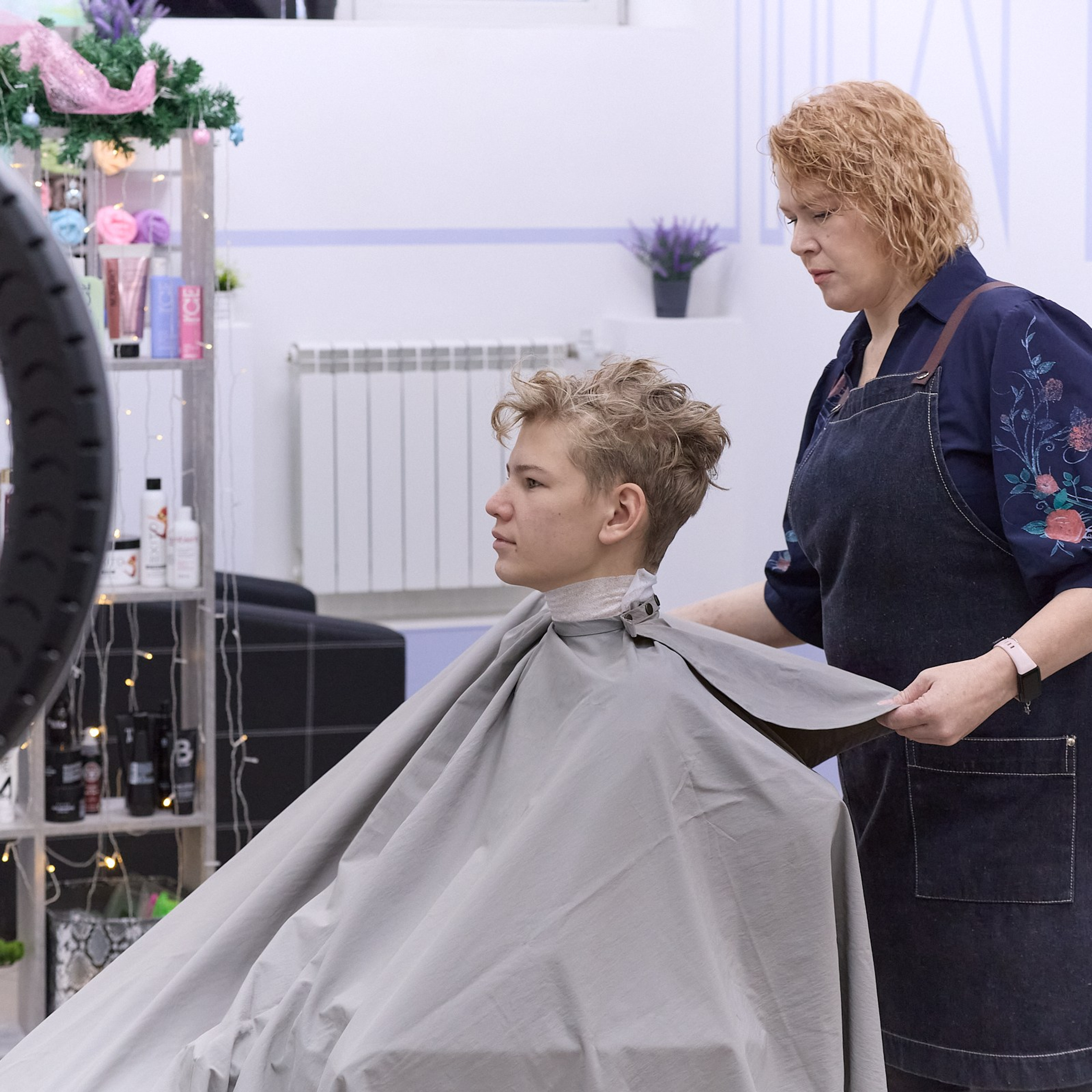 Парикмахер усаживает клиента в кресло. Съёмка для парикмахерской.