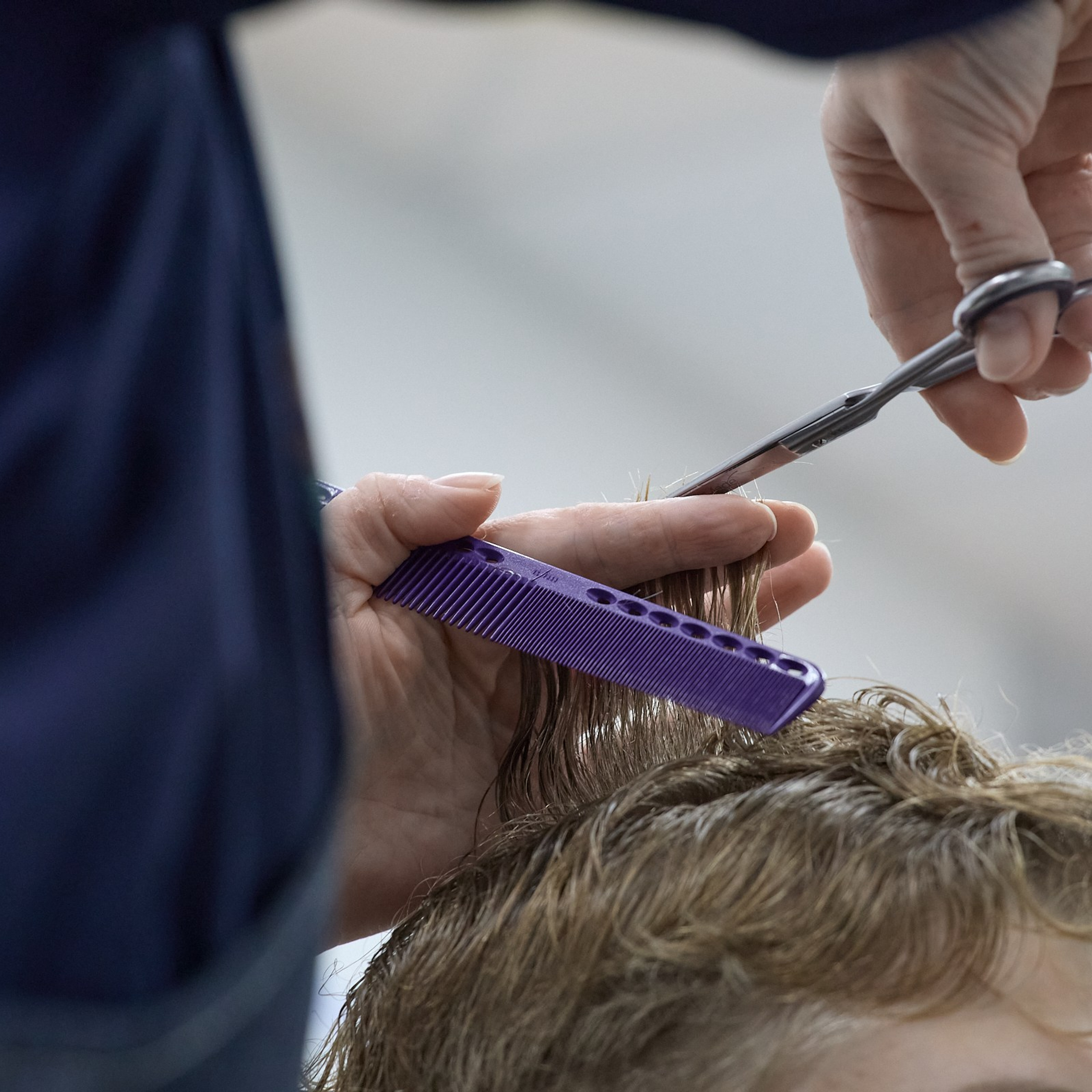 Парикмахер работает ножницами и расчёской.