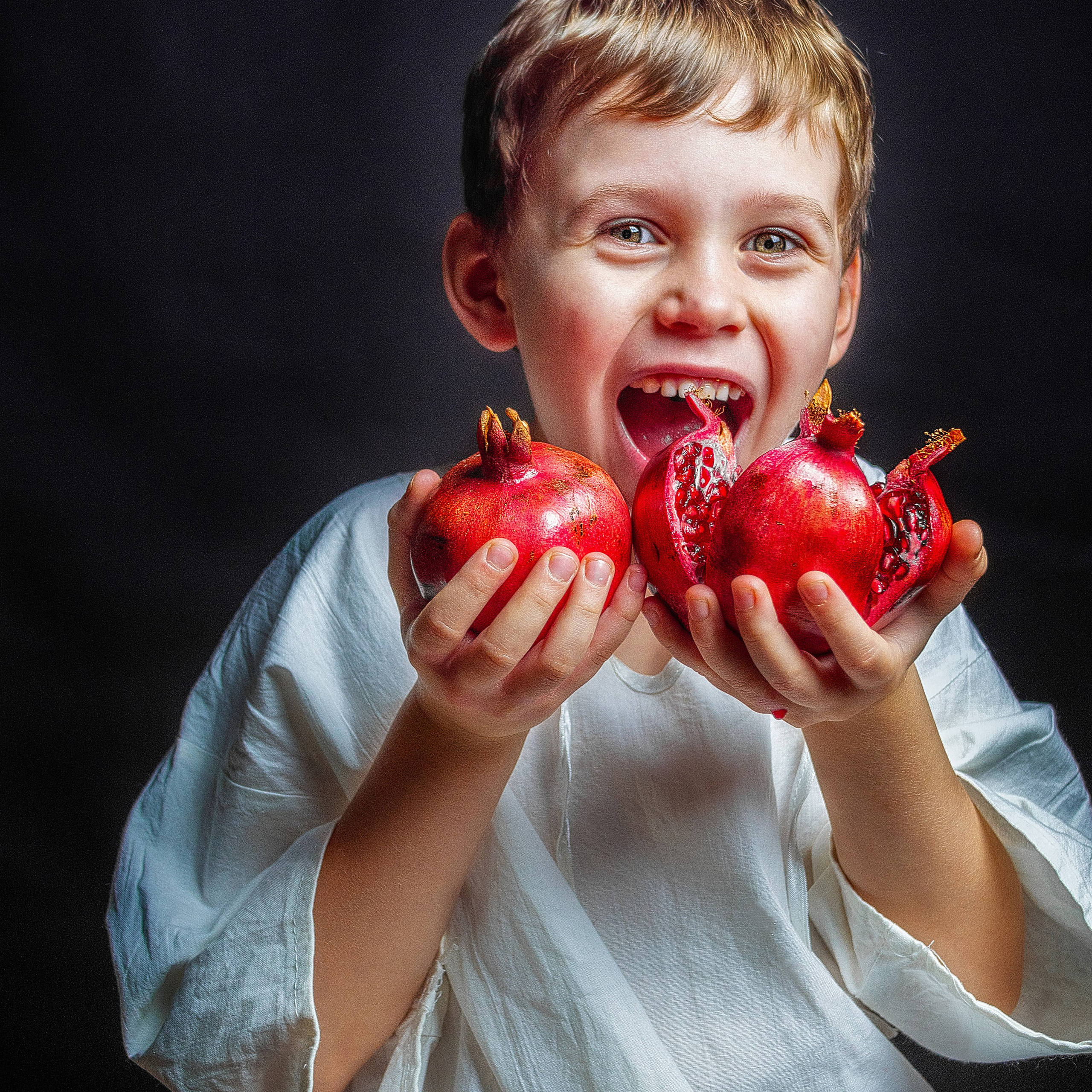 Фотосъемка с фруктами. Ребенок ест красный гранат.