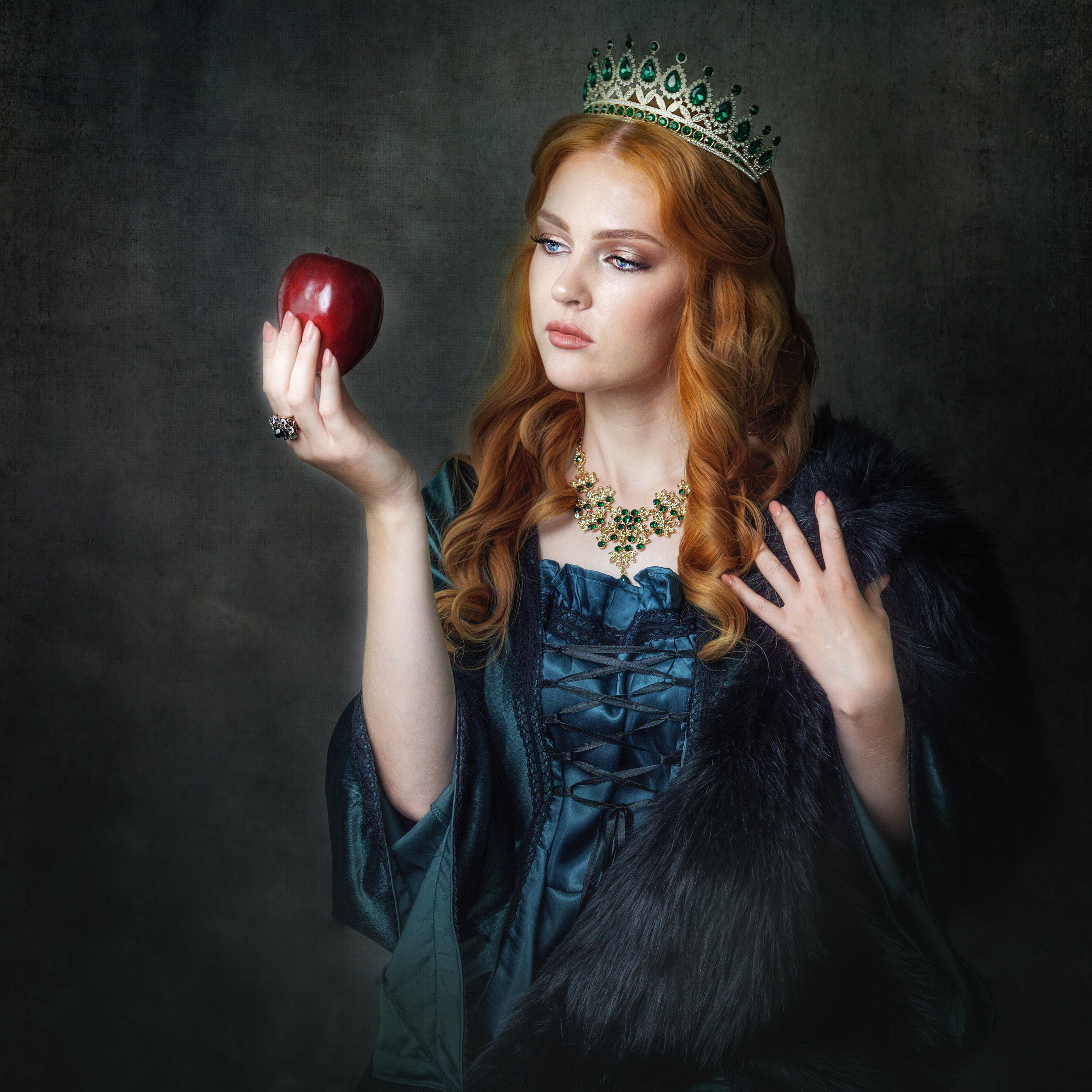 Королева держит ядовитое яблоко. Женская фотосессия в сказочных костюмах.