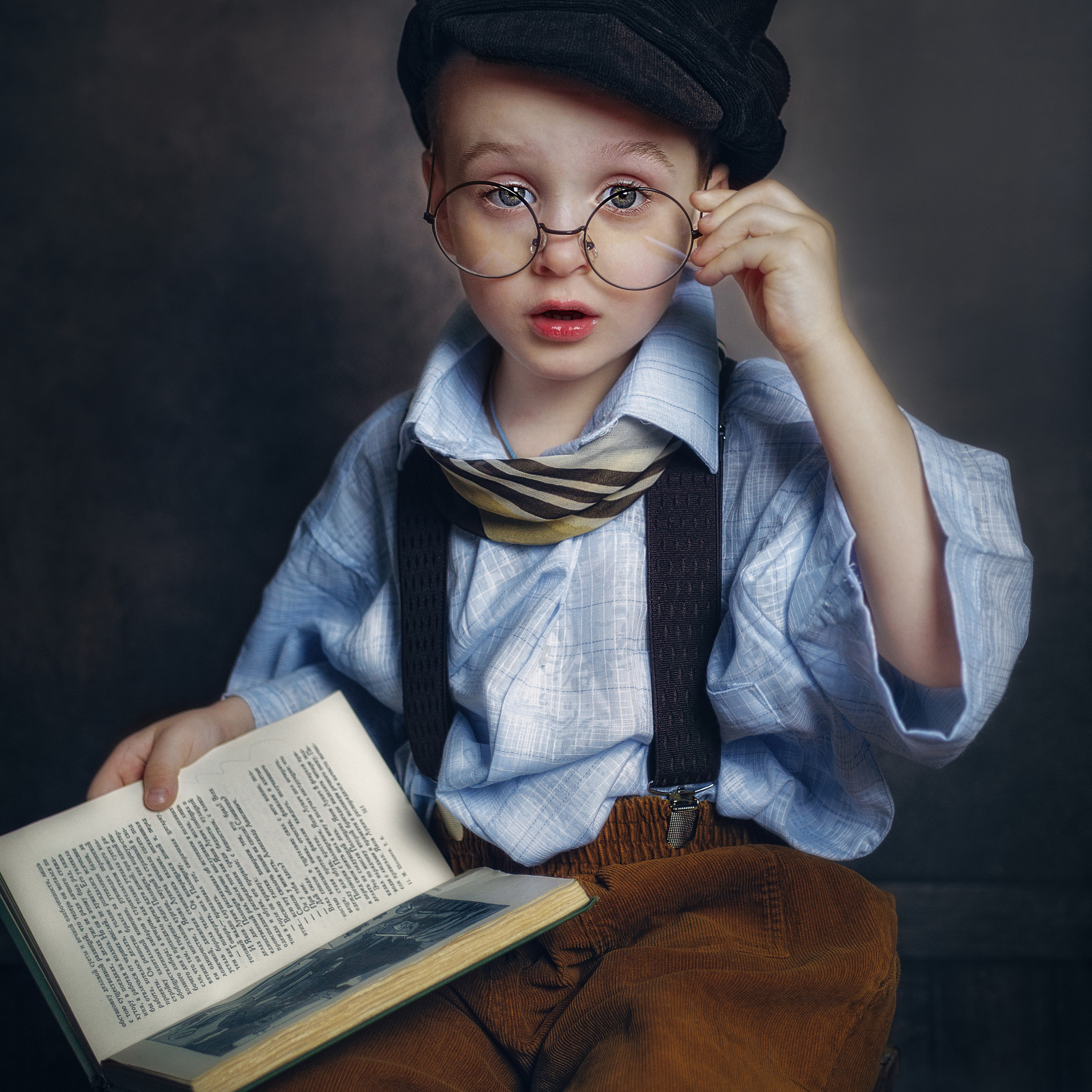 Винтажная съемка ребенка в очках с книгой.