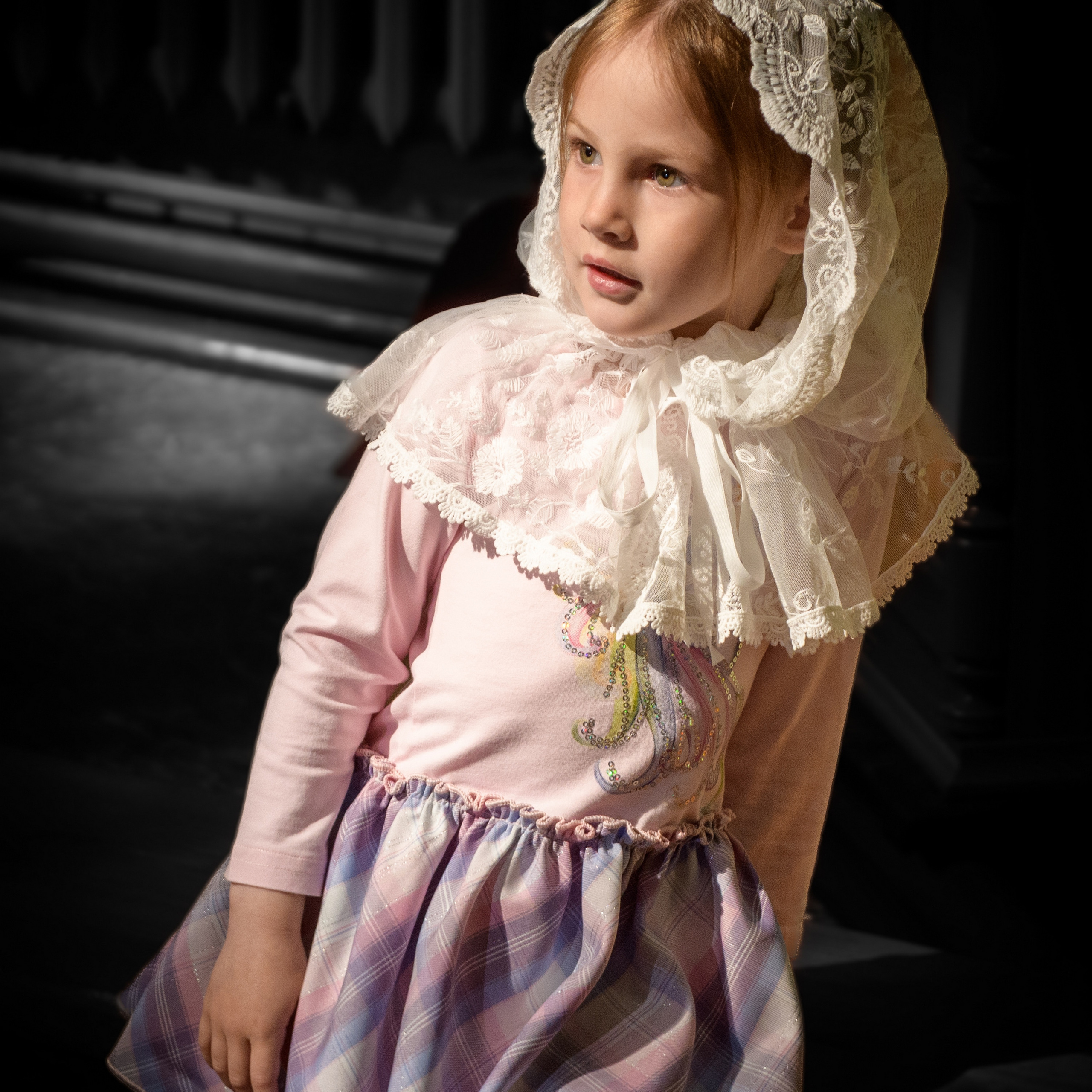 Девочка в церкви в лучах солнца смотрит в сторону от камеры