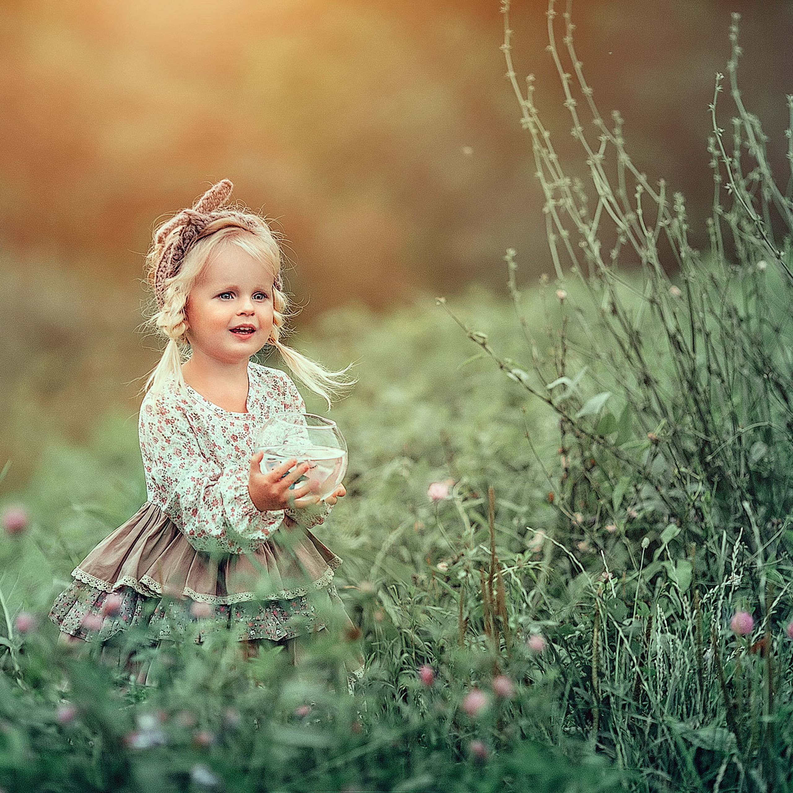 Рыжая русская  девушка с длинными волосами с черным конем летом в зеленом платье в траве в лесу в паркеМаленькая девочка в высокой траве держит в руках аквариум с рыбкой