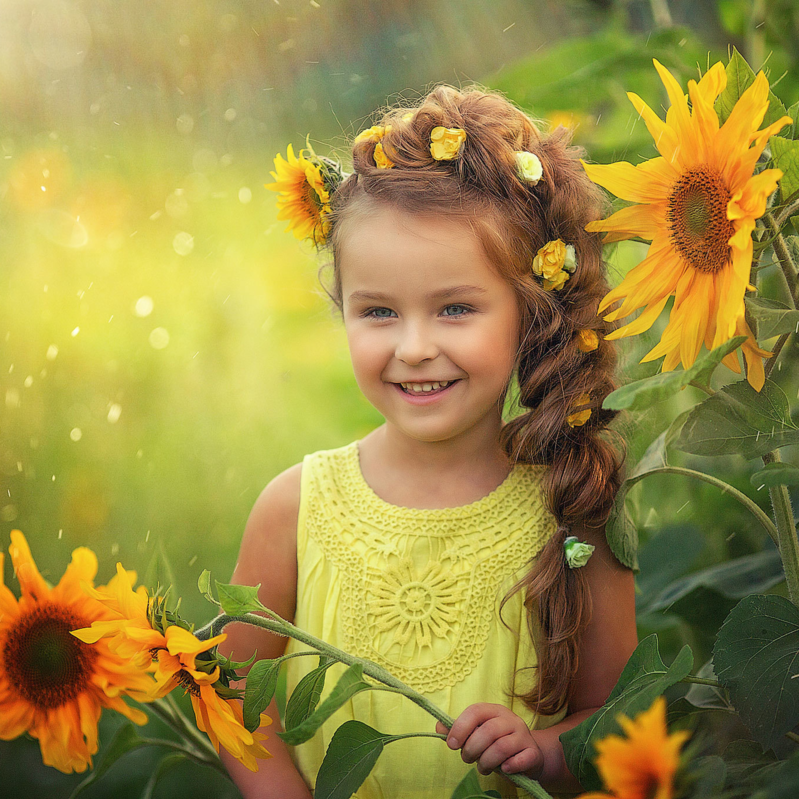 Девочка в желтом платье летом в парке с подсолнухами