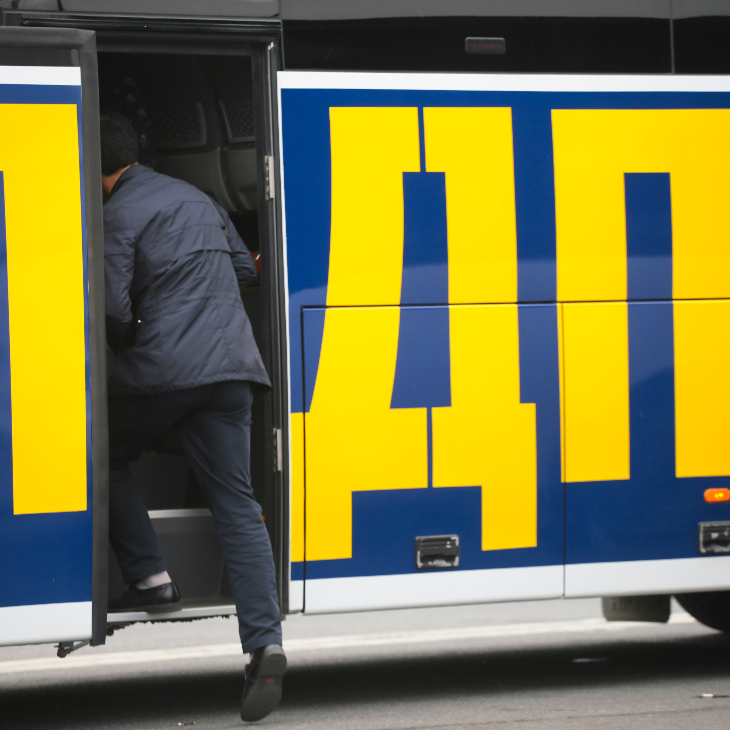 31 августа 2016 года. Санкт-Петербург. Человек в деловом костюме поднимается в автобус с рекламой политической партии "ЛДПР"