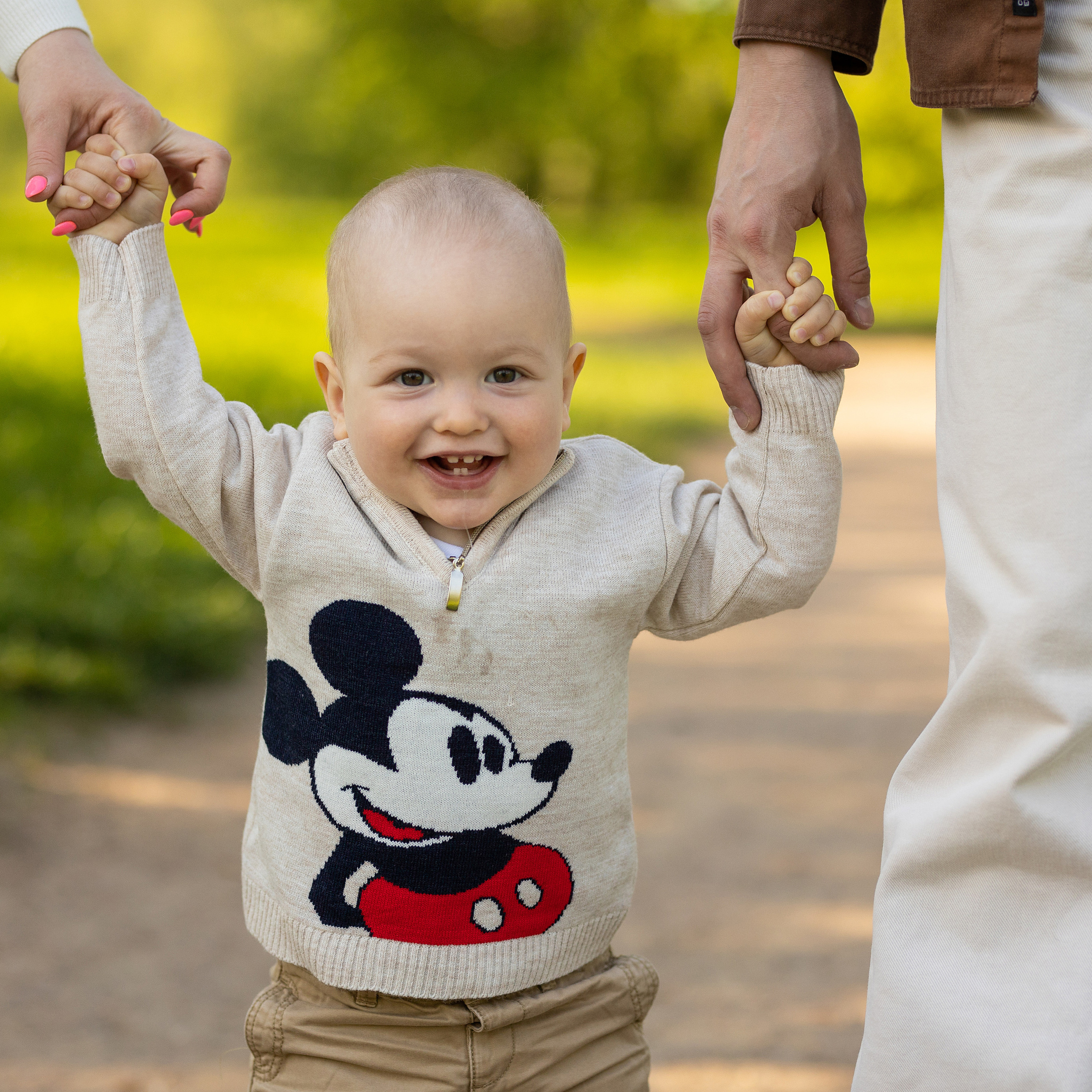 родители держат малыша за руки