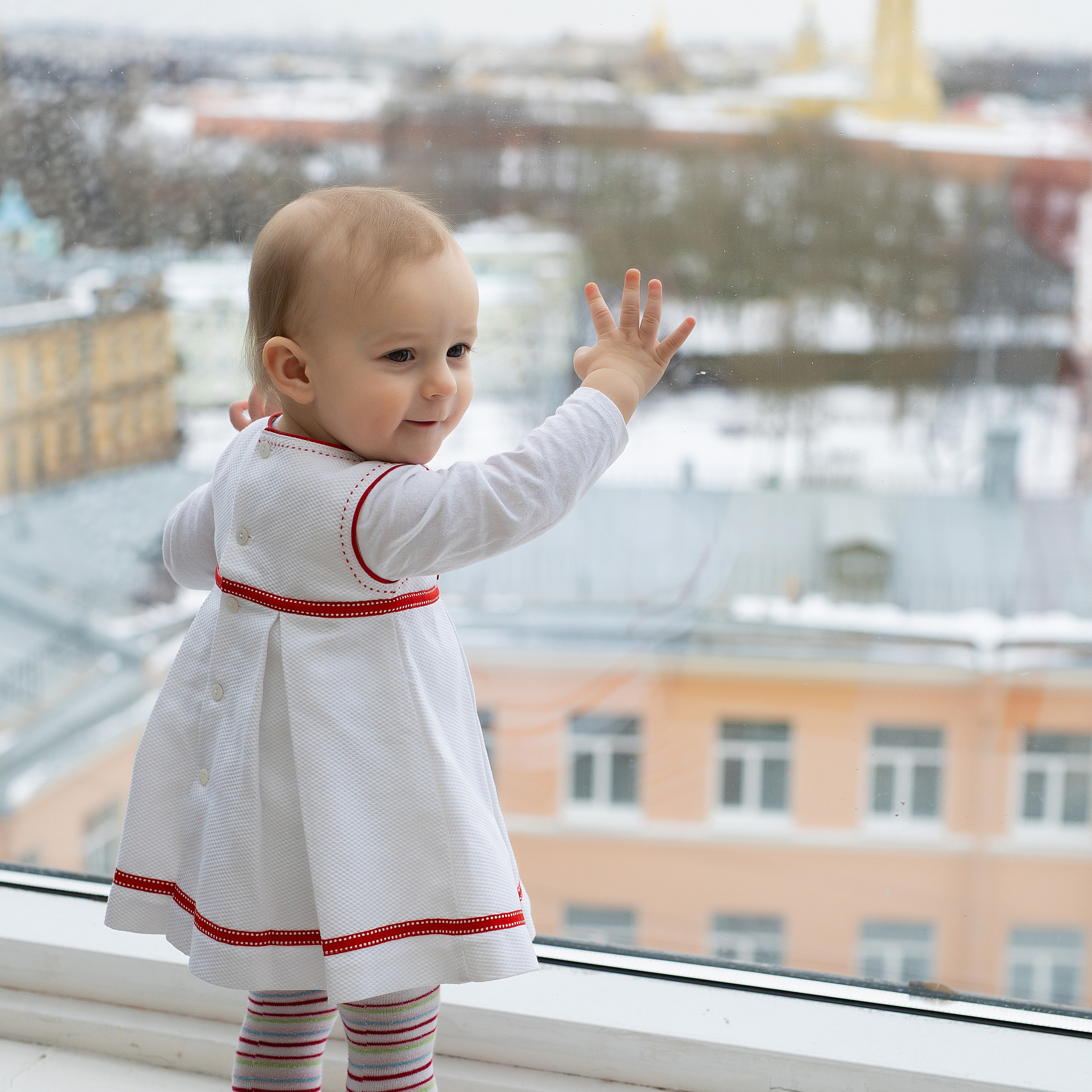 девочка смотрит в окно на город