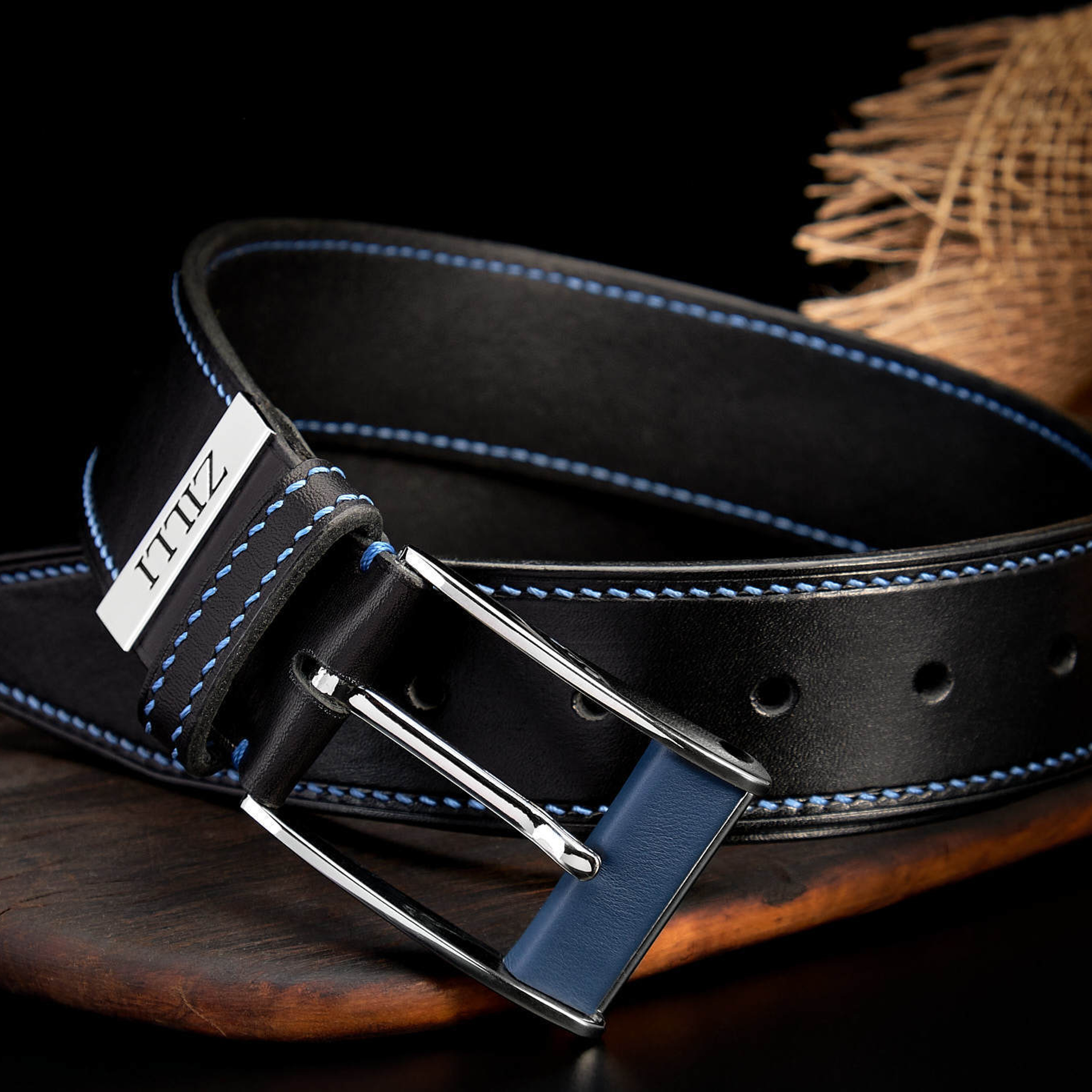 Чёрный кожаный ремень с пряжкой на фоне мешковины