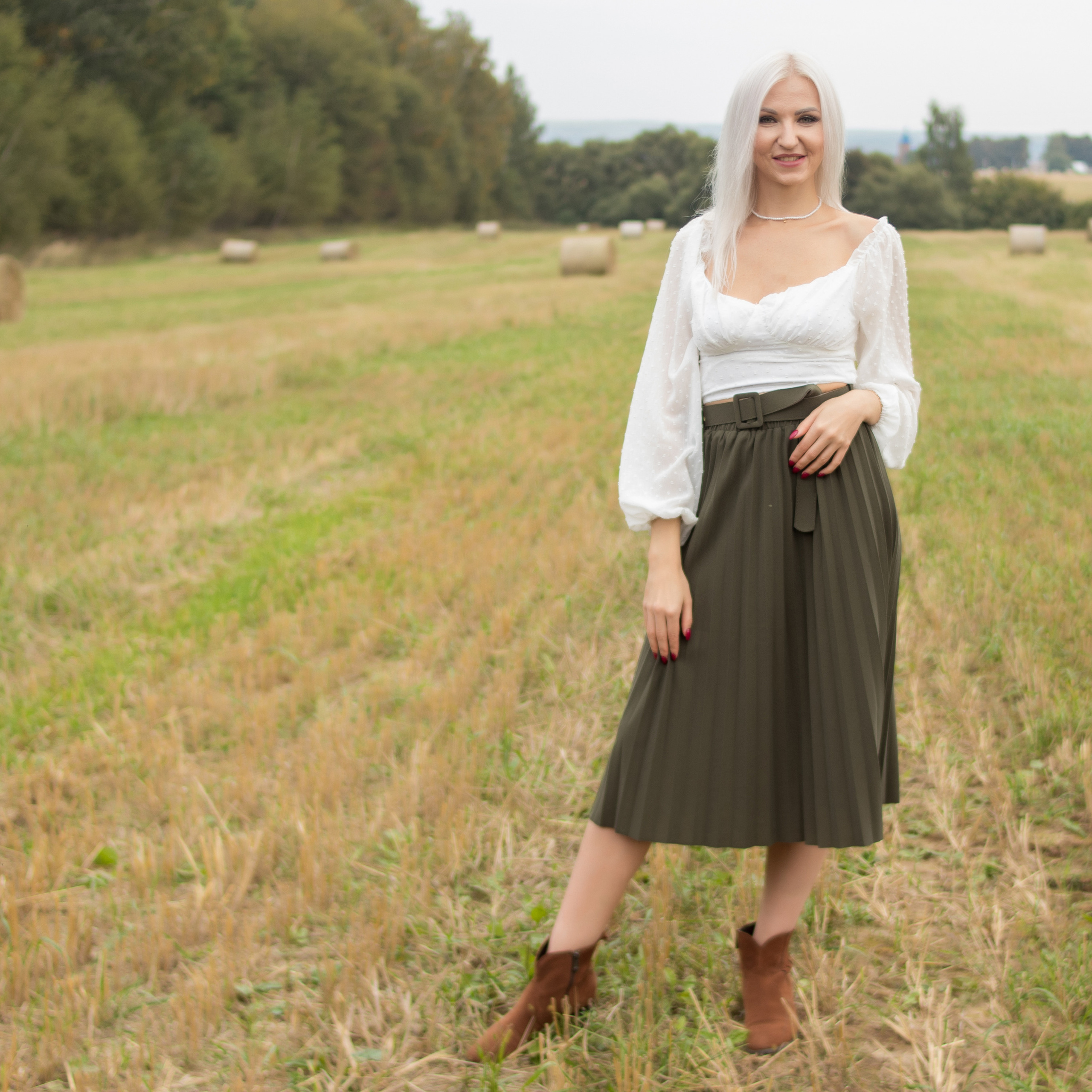 Елена в поле с рулонами сена