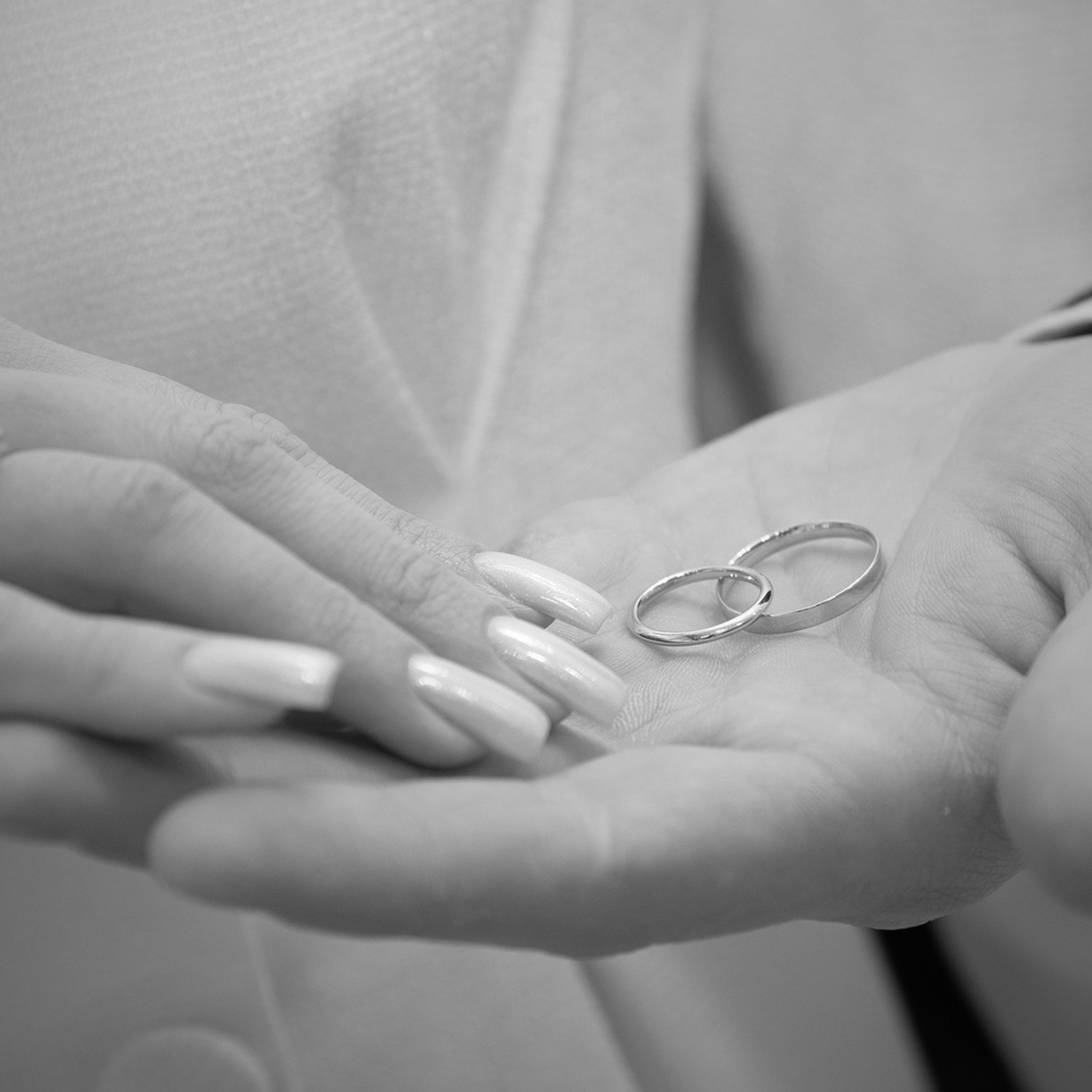 черно белое фото где на регистрации брака фотограф снял невесту которая держит за руку жениха у которого на руке лежат кольца 