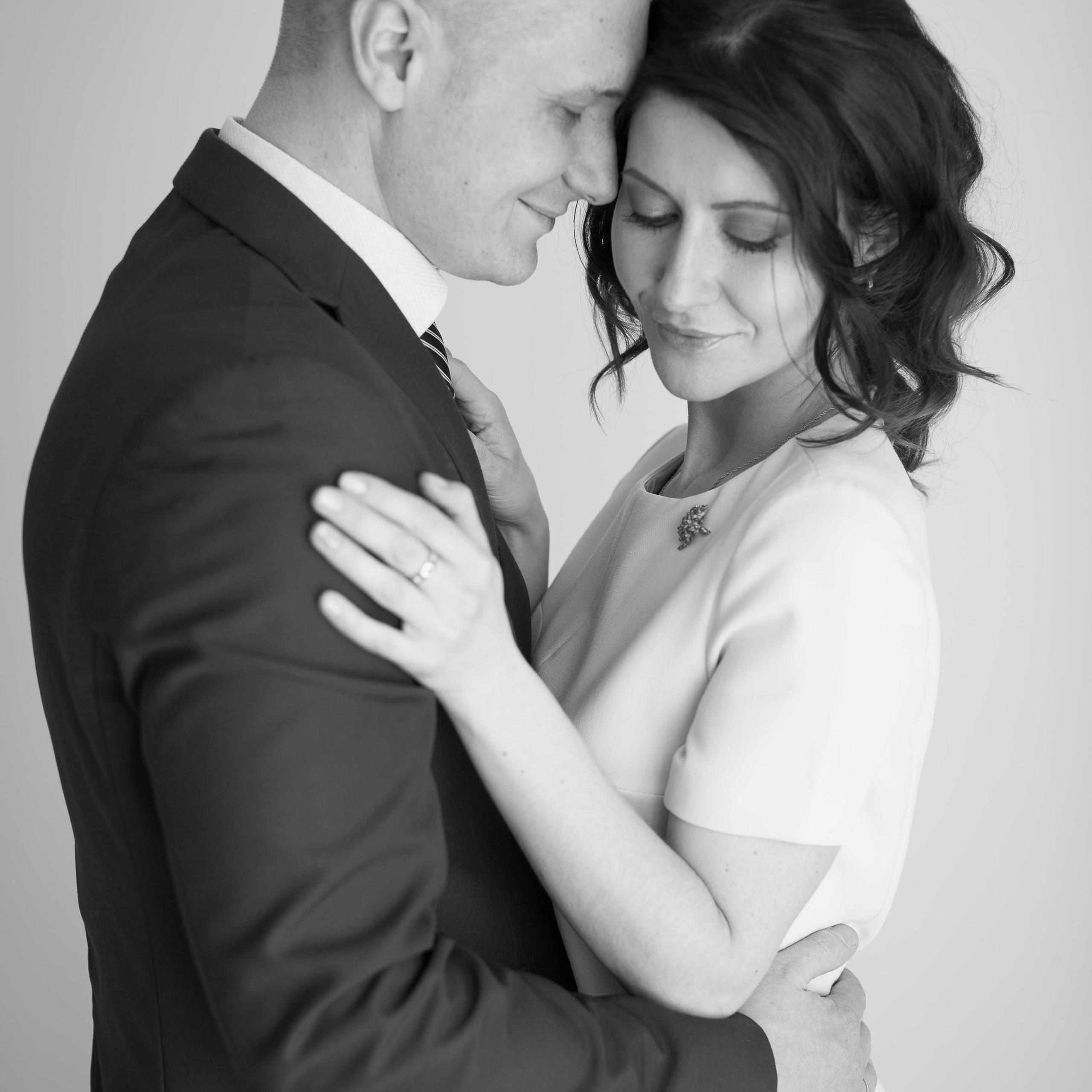 Фотосессия красивой влюбленной семейной пары в домашней фотостудии в приморском районе в Санкт-Петербурге в черно белом стиле, они стоят и нежно обнимаются