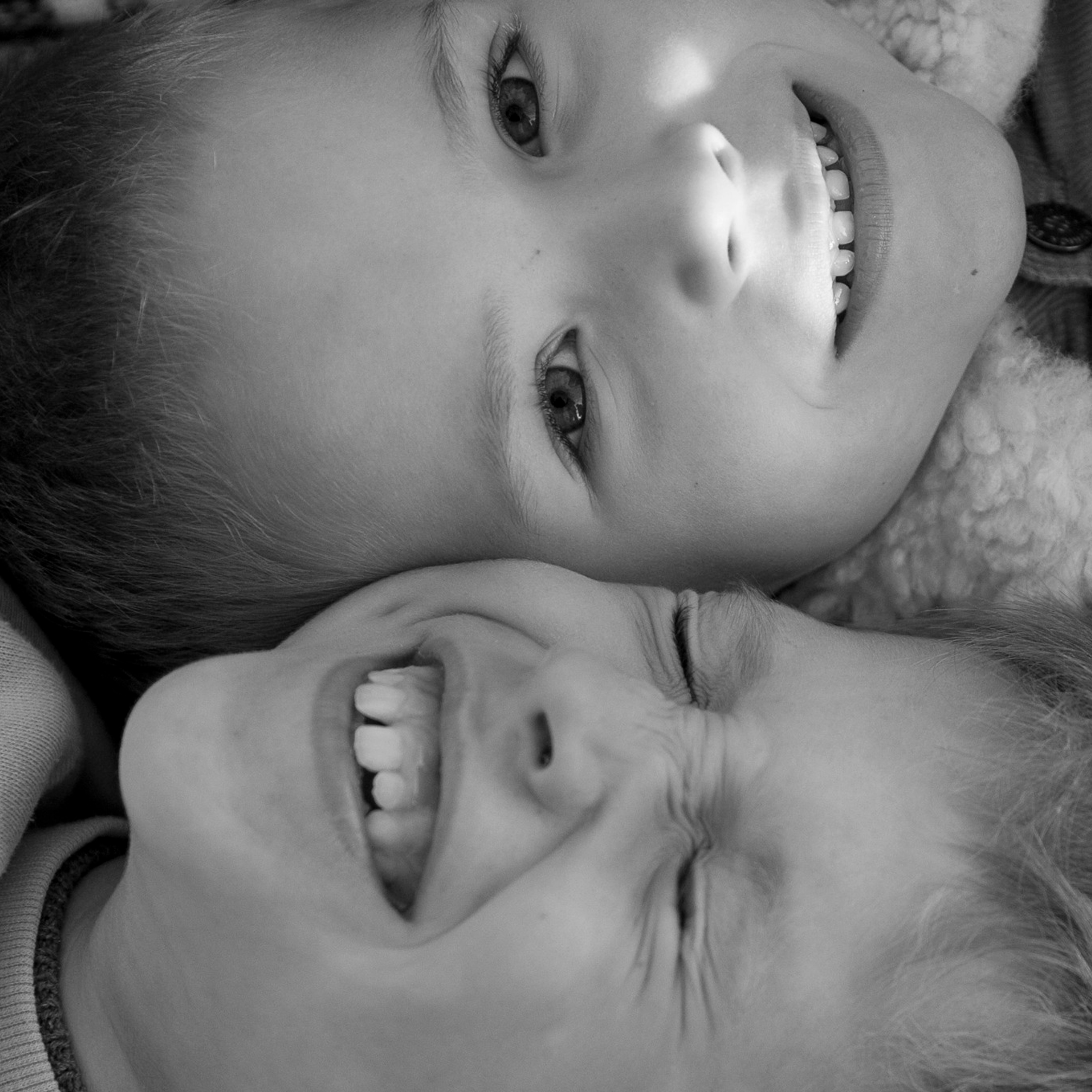 Два братика лежат на осенних листьях и смеются