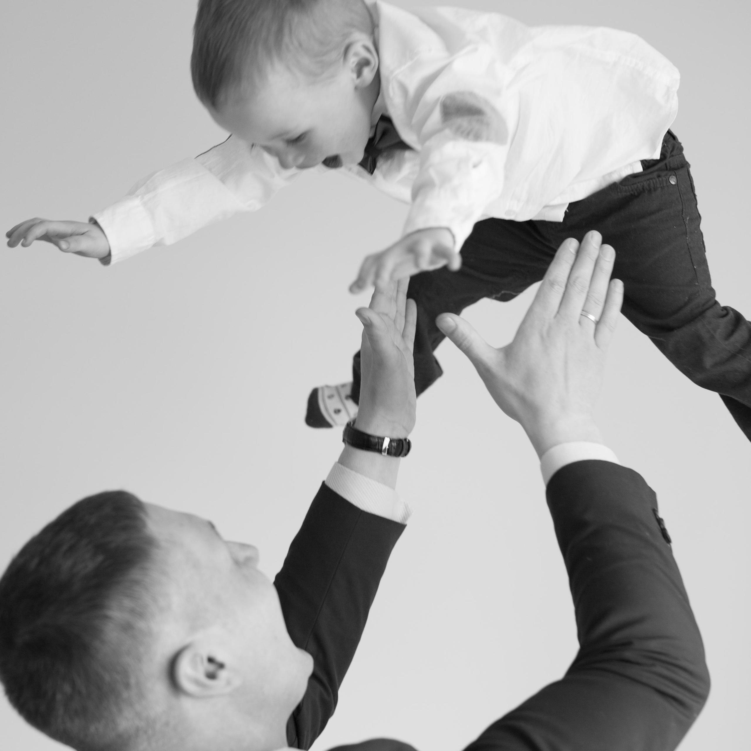 Семейная фотосъемка папа подкидывает  на руках сына, а он заливисто хохочет 