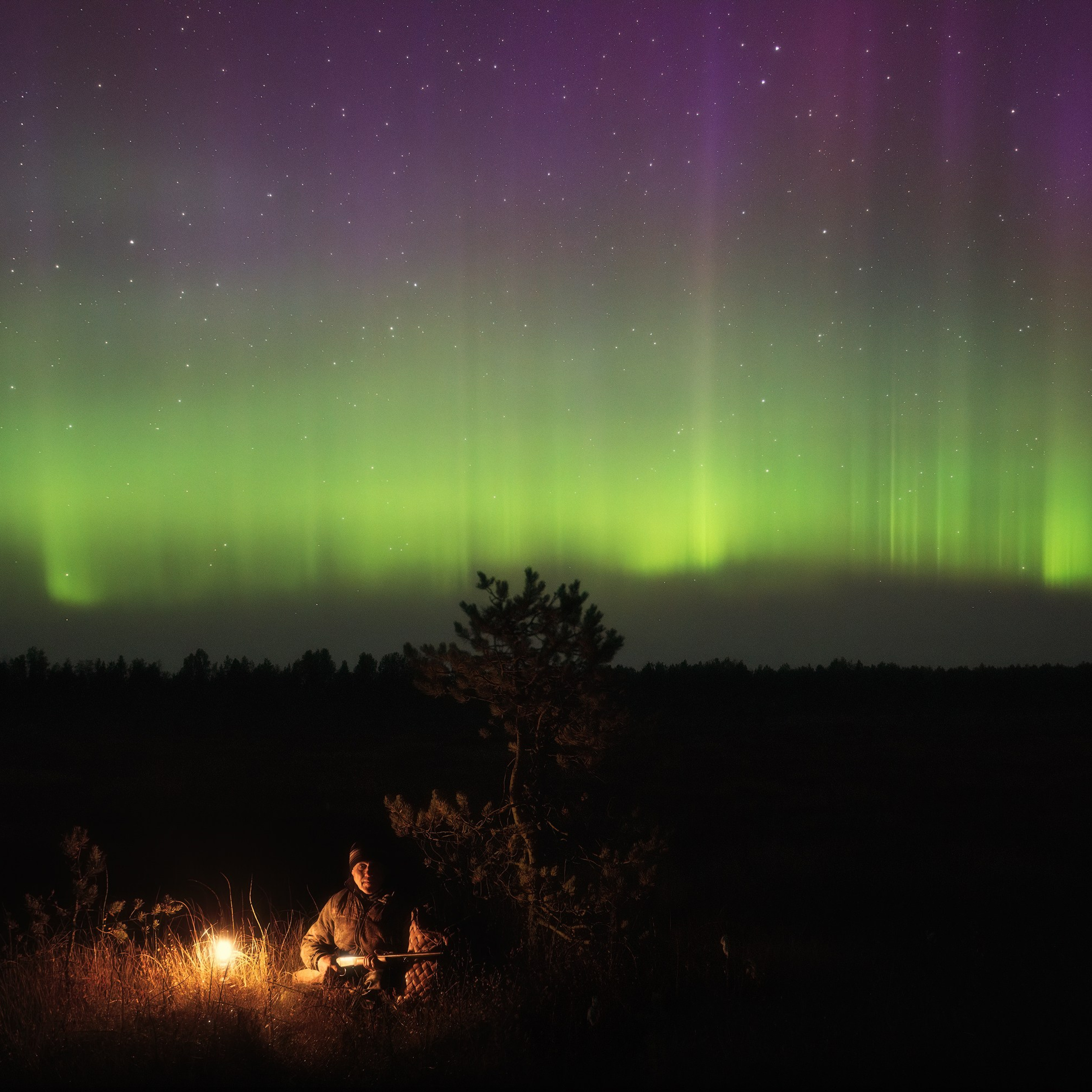 A hunter with a gun in autumn. A hunter and the northern lights. A hunter with a kerosene lamp at night.