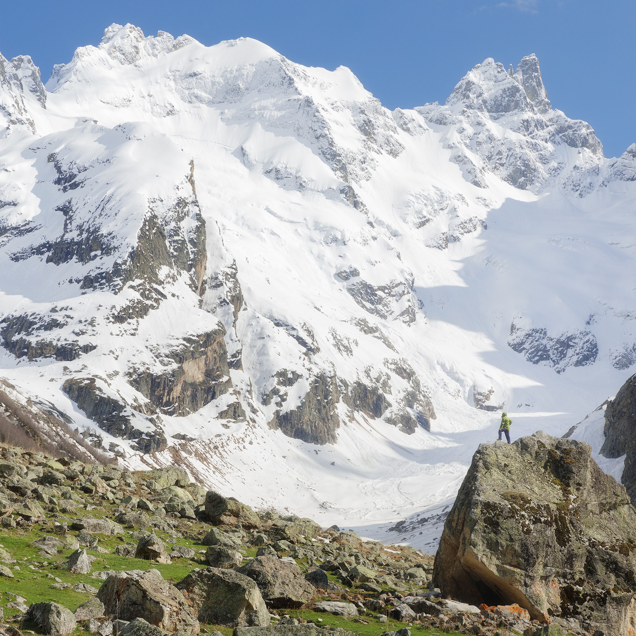 Ущелье Узункол. Человек на фоне горы. Кавказские горы в Карачаево-Черкесской Республике. Маленький человек на фоне огромной белой горы. Северный Кавказ. Горный пейзаж.