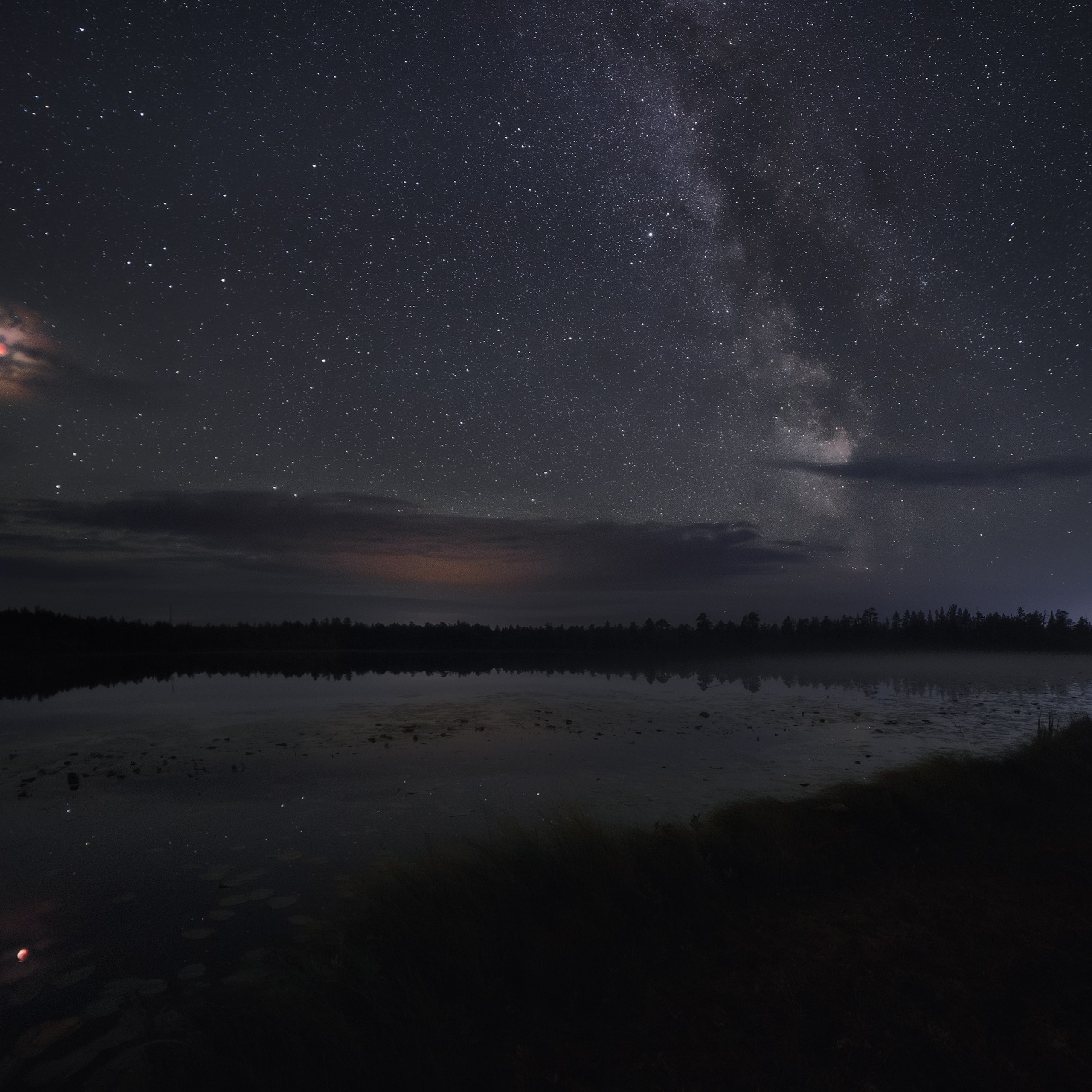 Milky Way. Lunar eclipse. Bright meteor. Lunar eclipse and the Milky Way over a lake. Starry night over a lake. A bright fireball flies over a lake. Eclipse over a lake.