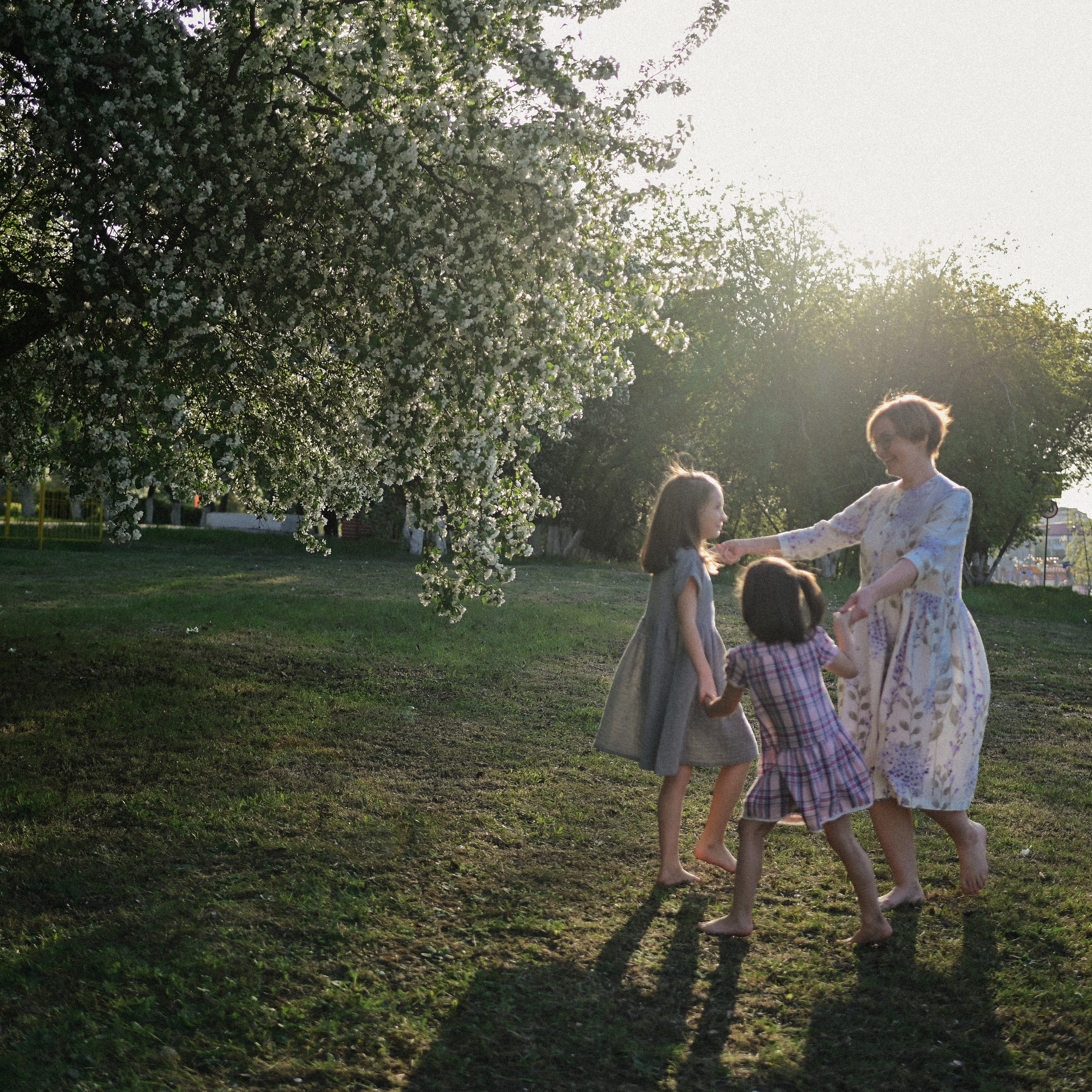 Фотосессия мамы и двух дочек в цветущих яблонях