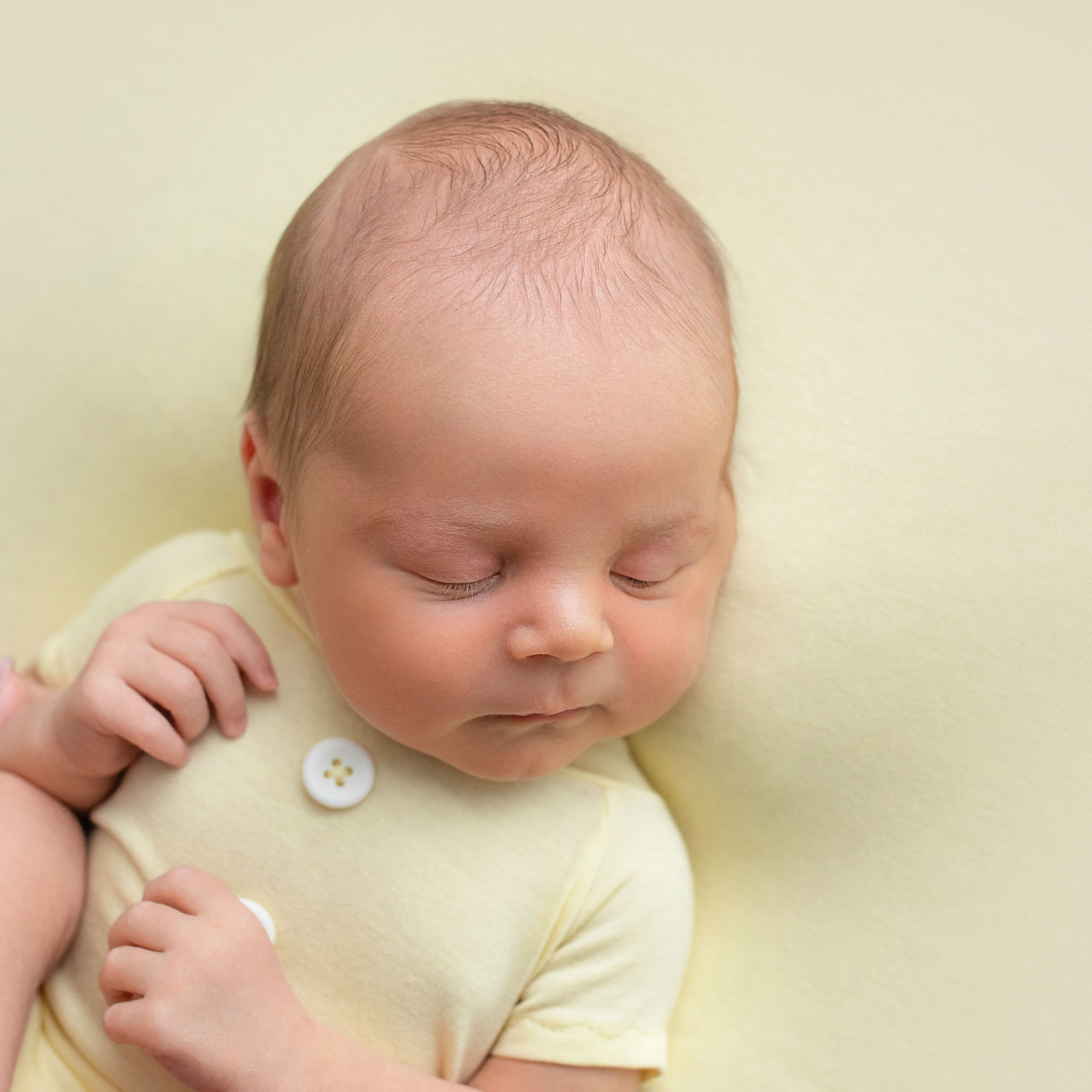 новорожденный на желтом тканевом фоне