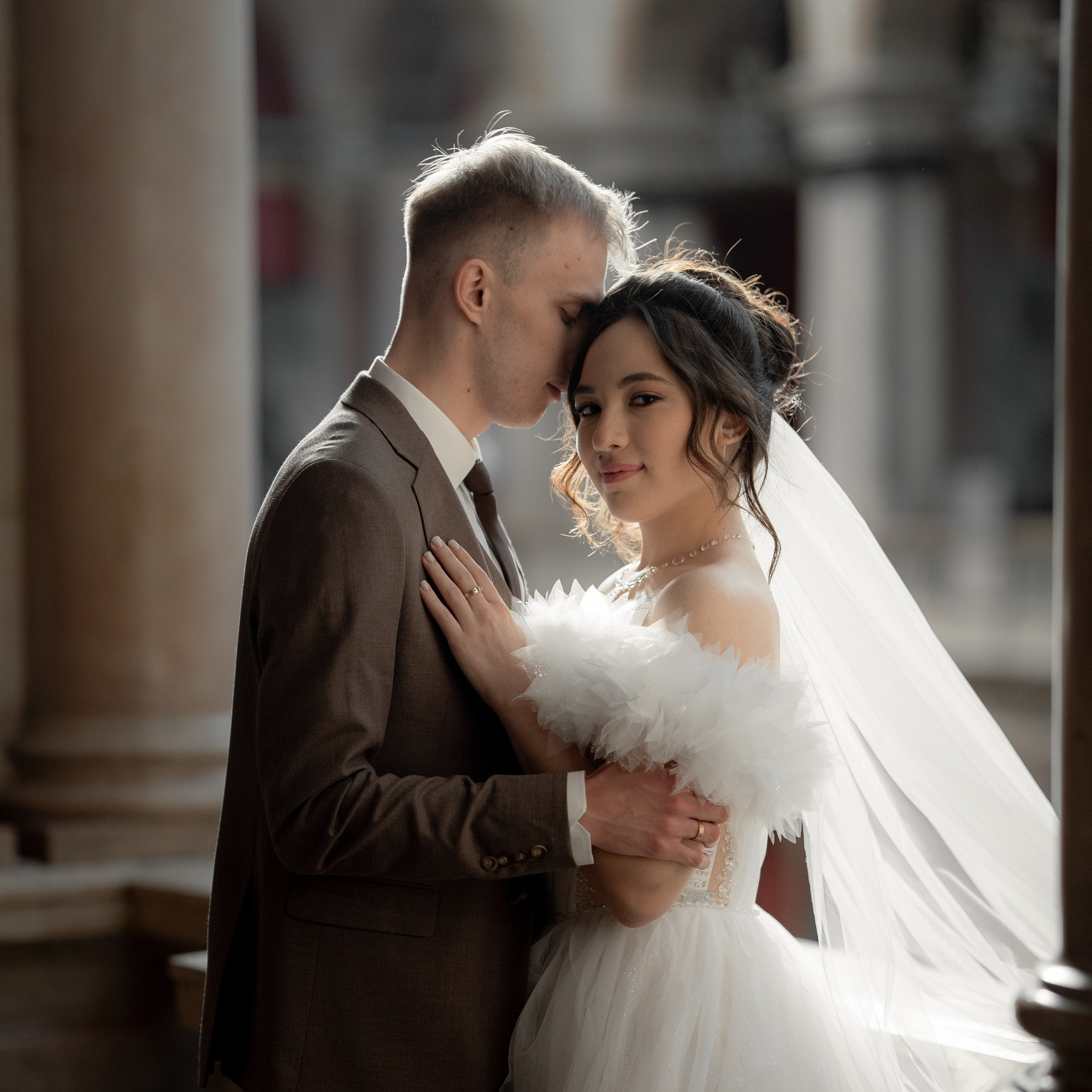 Свадебная фотосессия в академии Штиглица жених обнимает невесту в лучах контрового света