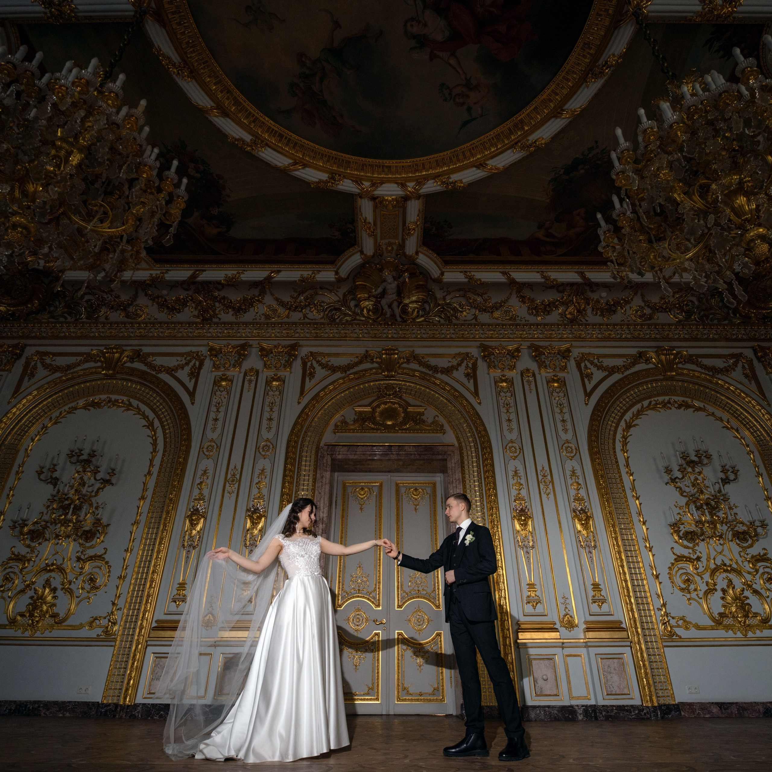 Свадебная фотосессия в особняке Половцева (дом Архитектора) невеста и жених танцуют в большом зале с золотыми люстрами снято на широкоугольный объектив