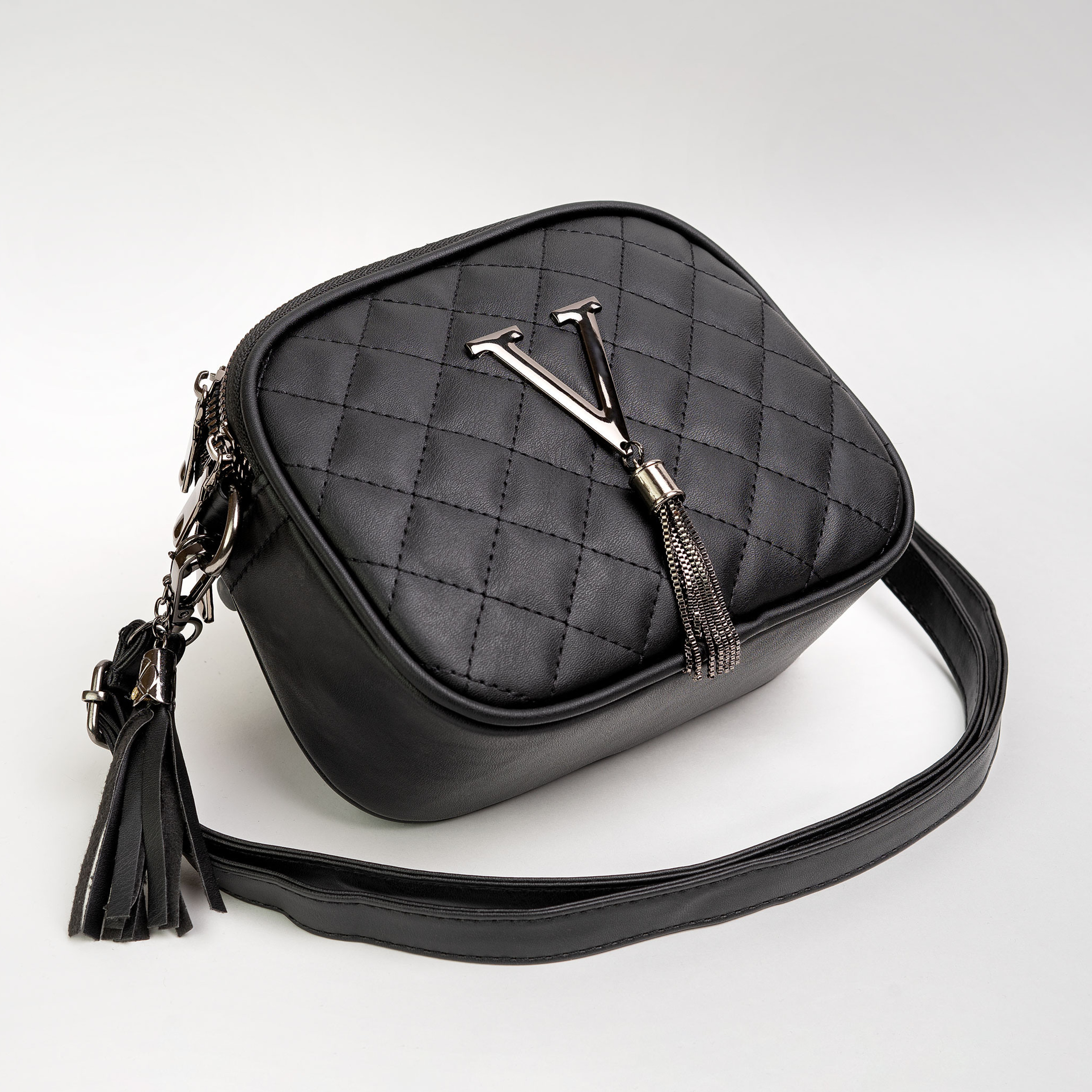 Чёрная кожаная сумка на белом фоне снята под наклоном 