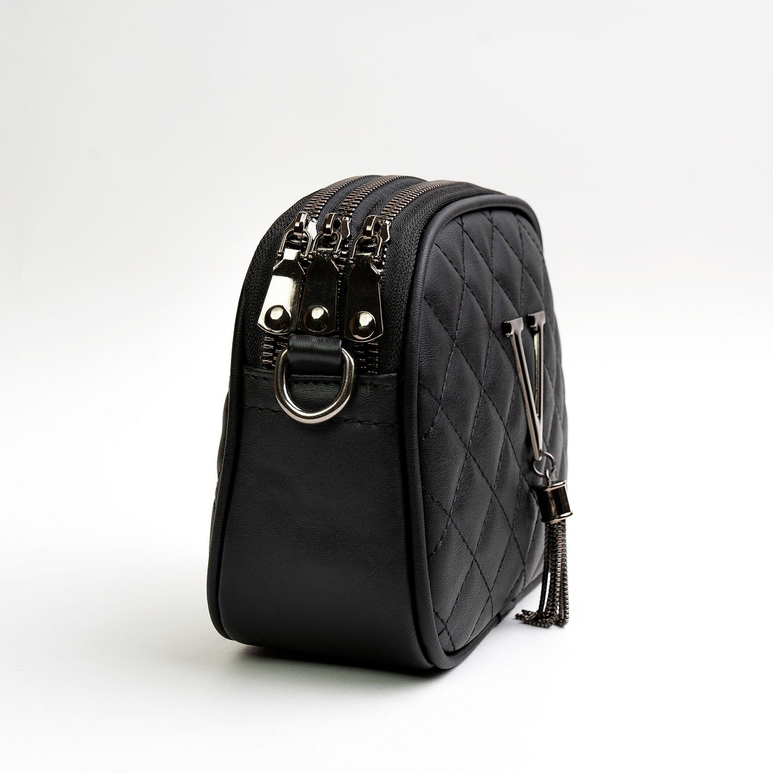 Чёрная кожаная сумка на белом фоне снятая с торца