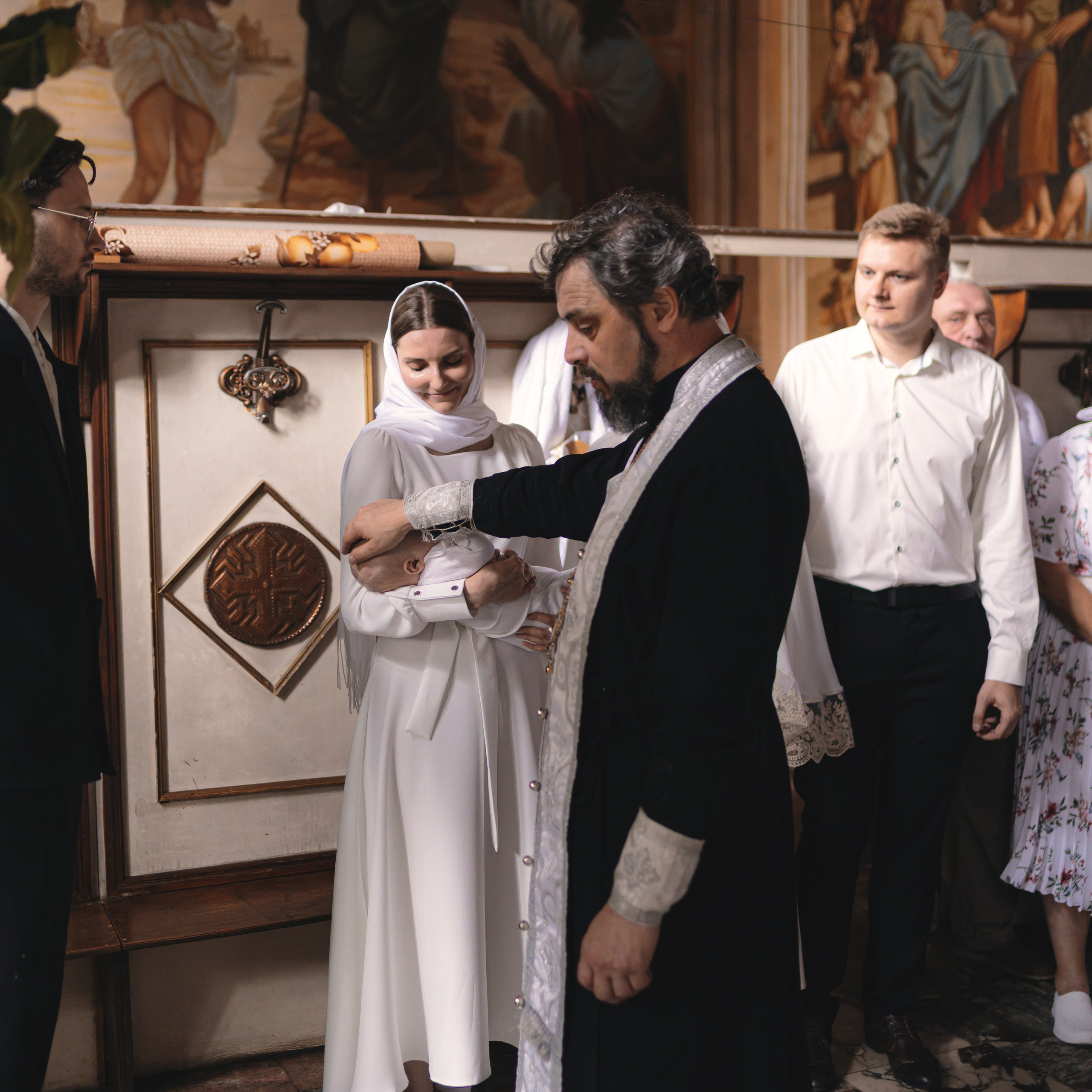 Крёстные держат ребёнка на руках во время Таинства Крещения. Светлый и важный момент для семьи.