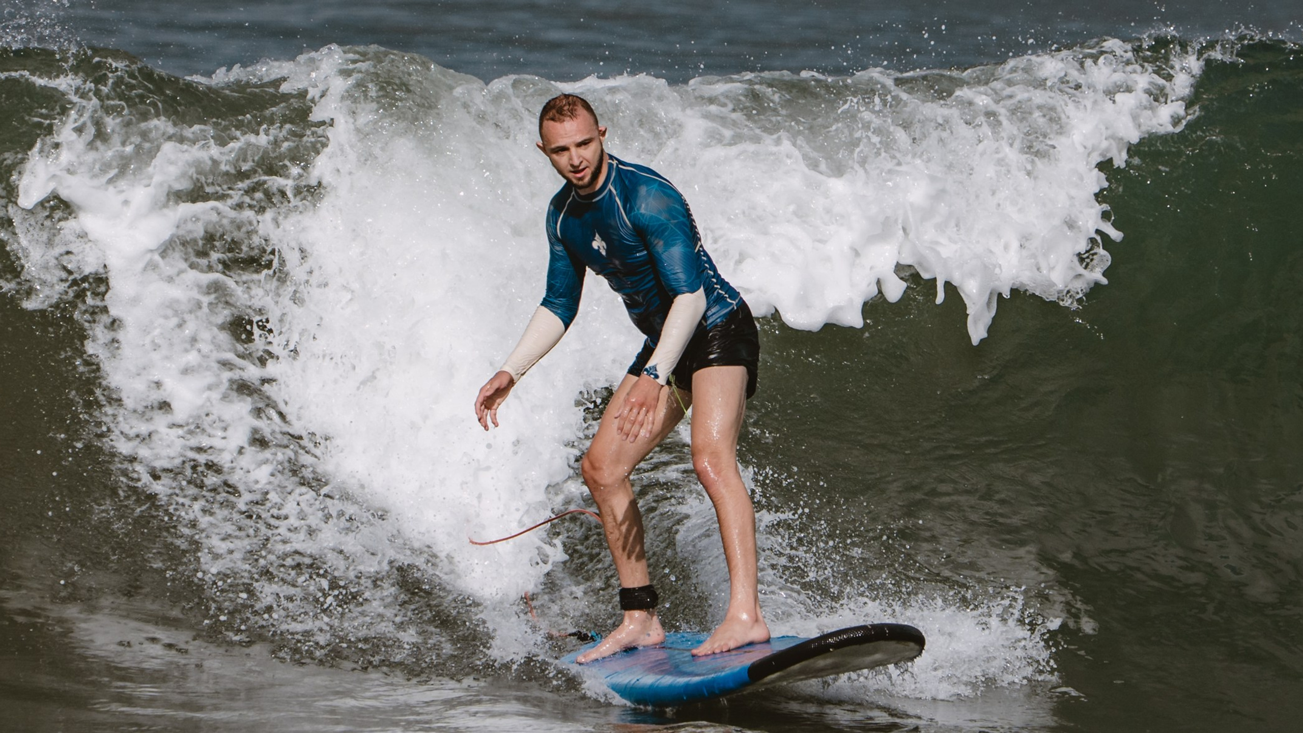 Mixed martial artists having fun surfing at the ocean in between training sessions