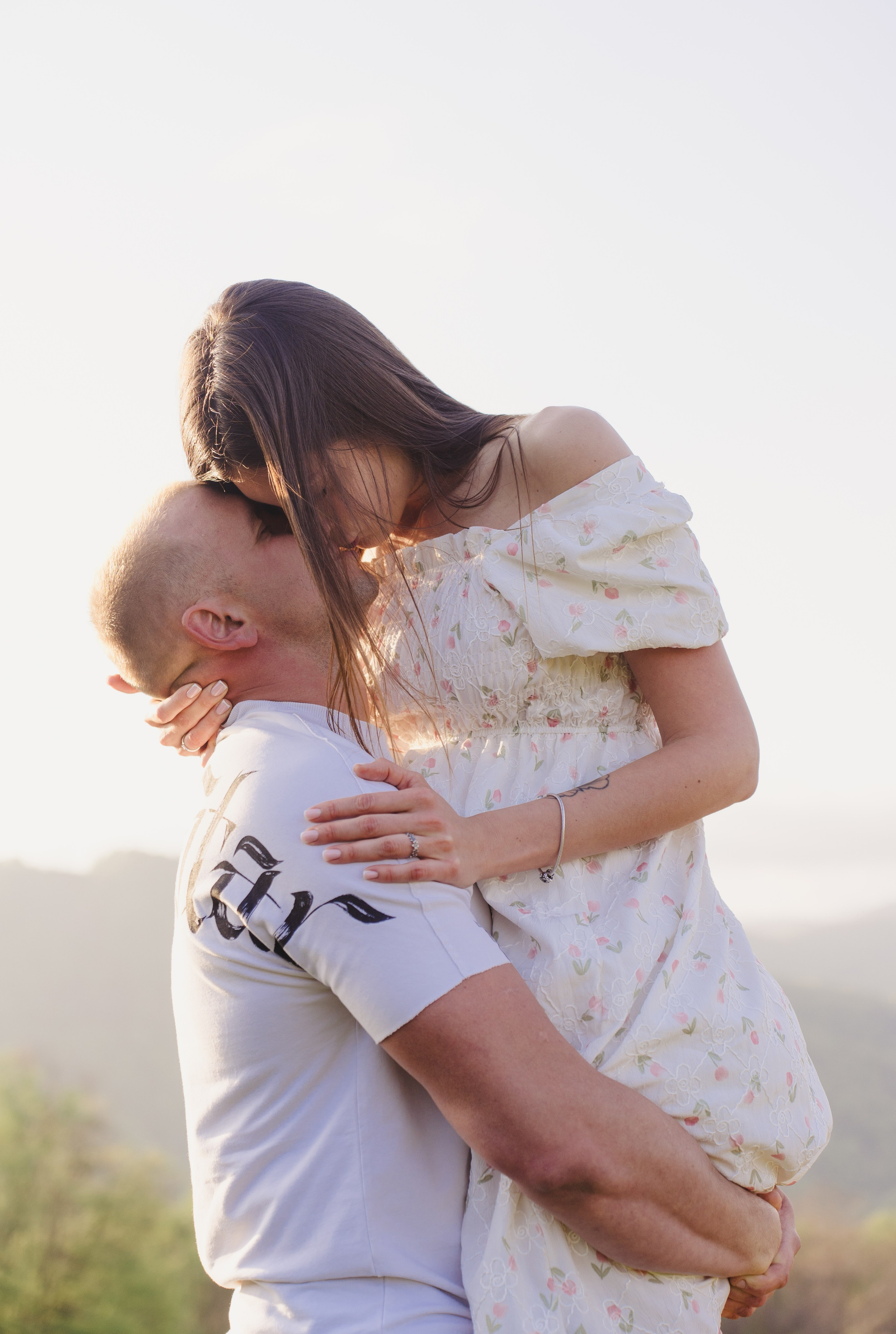 На этой фотографии изображен мужчина, несущий женщину на руках, и они целуются друг друга. Образ создает впечатление романтики и заботы, возможно, это момент радостного события, такого как свадьба или просто искренний жест любви. Обстановка может быть уютной и спокойной, что дополняет атмосферу нежности между главными персонажами.