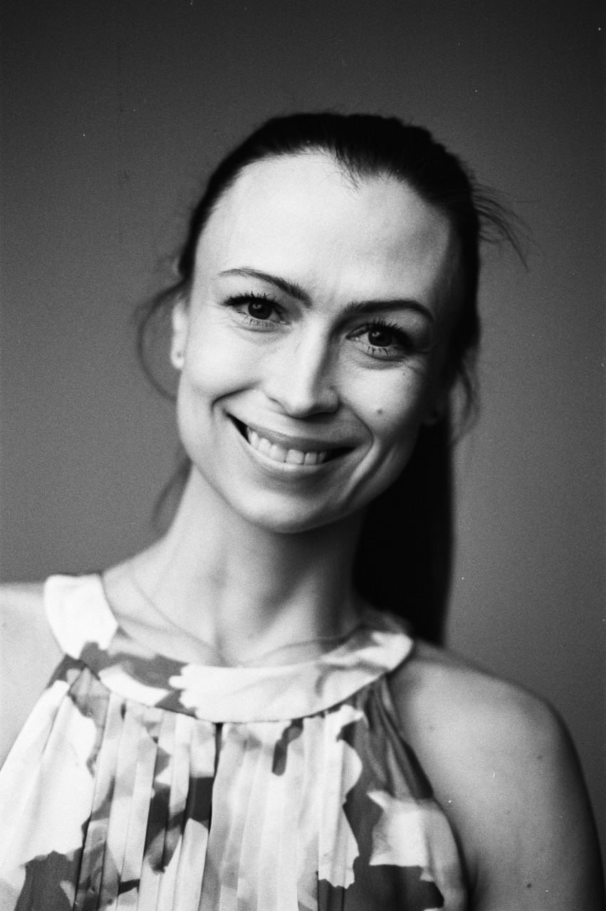 Женский портрет с улыбкой, выполненный в черно-белой пленочной эстетике.