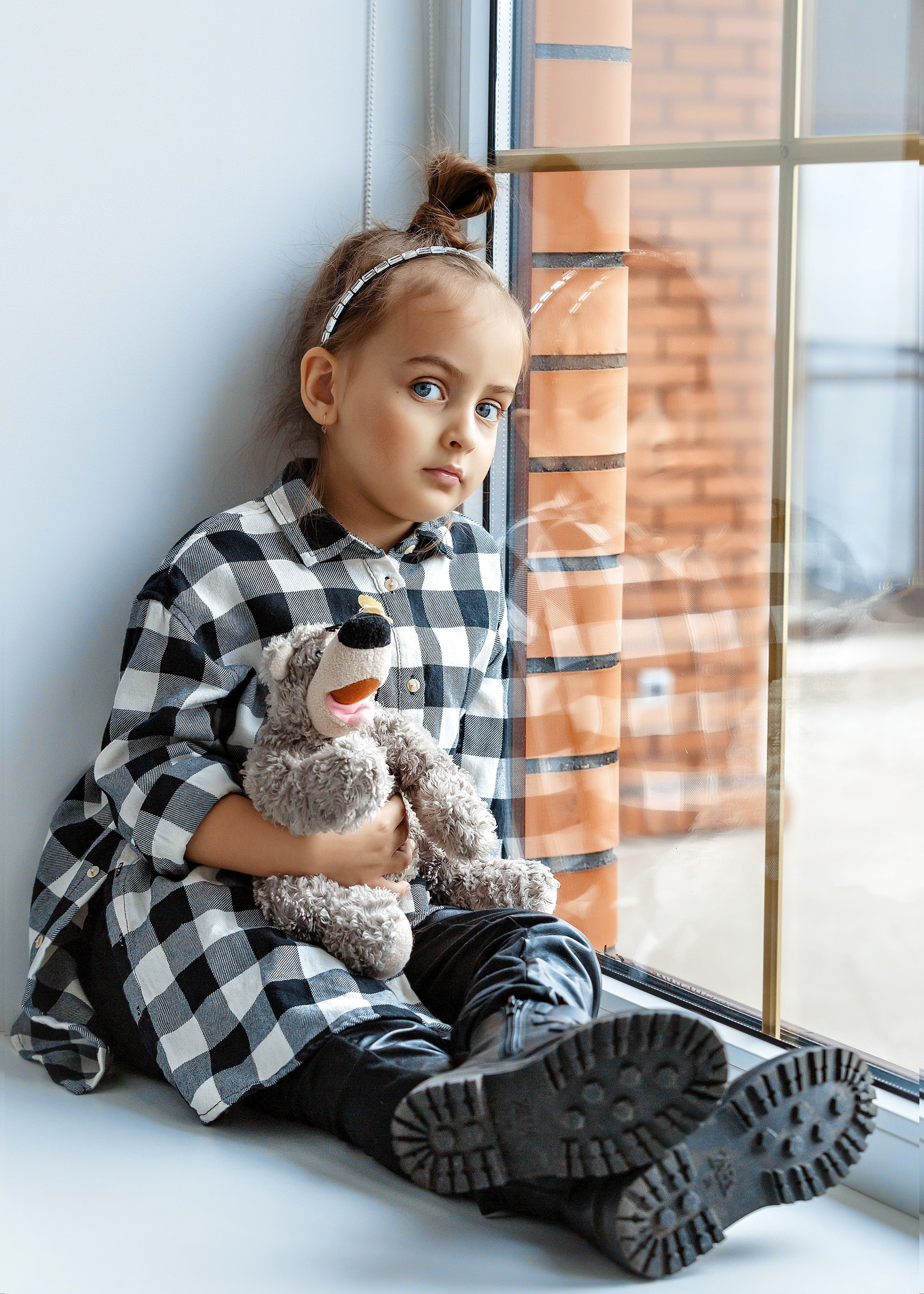 девочка с игрушкой сидит на подоконнике