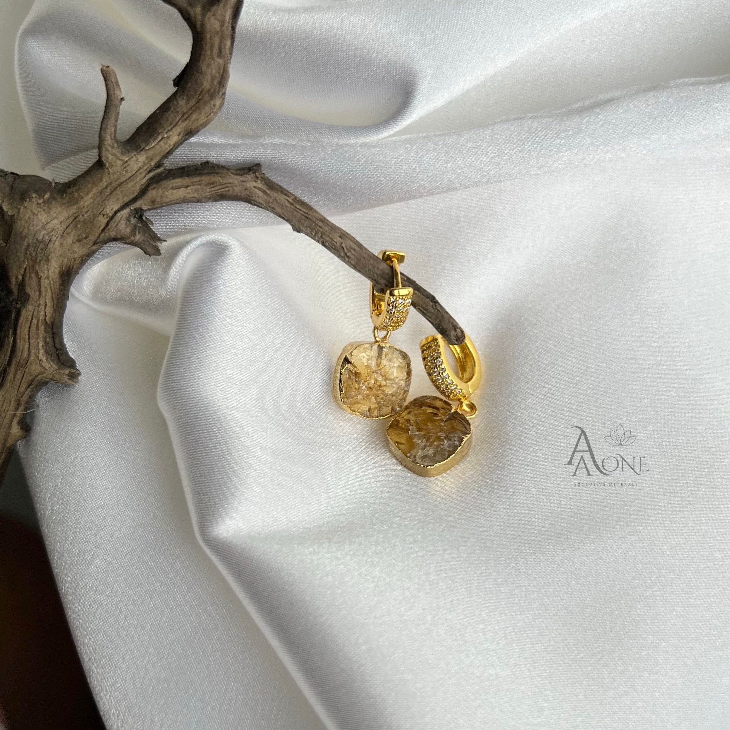 А серьги с цитрином лежат на белом фоне это солнечный камень который поможет улучшить здоровье