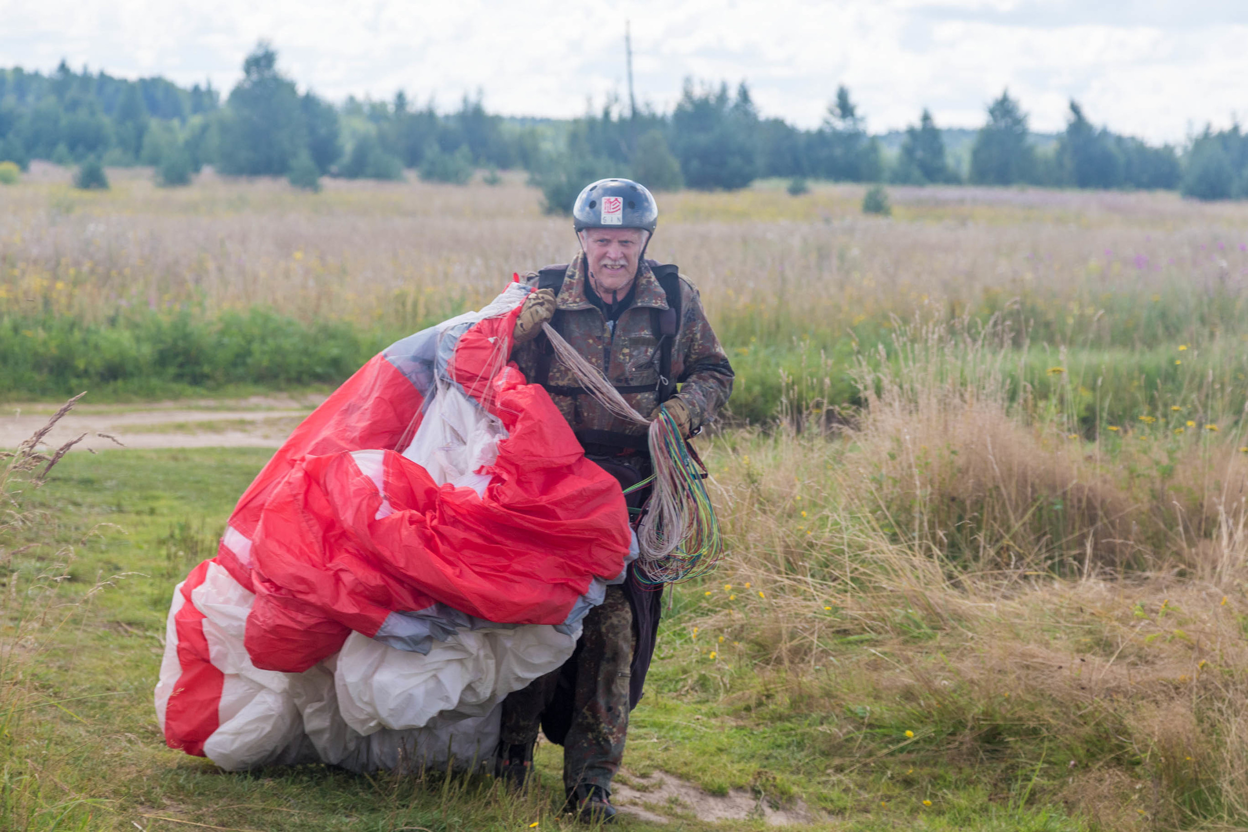 Пилот параплана несет свой парашют
