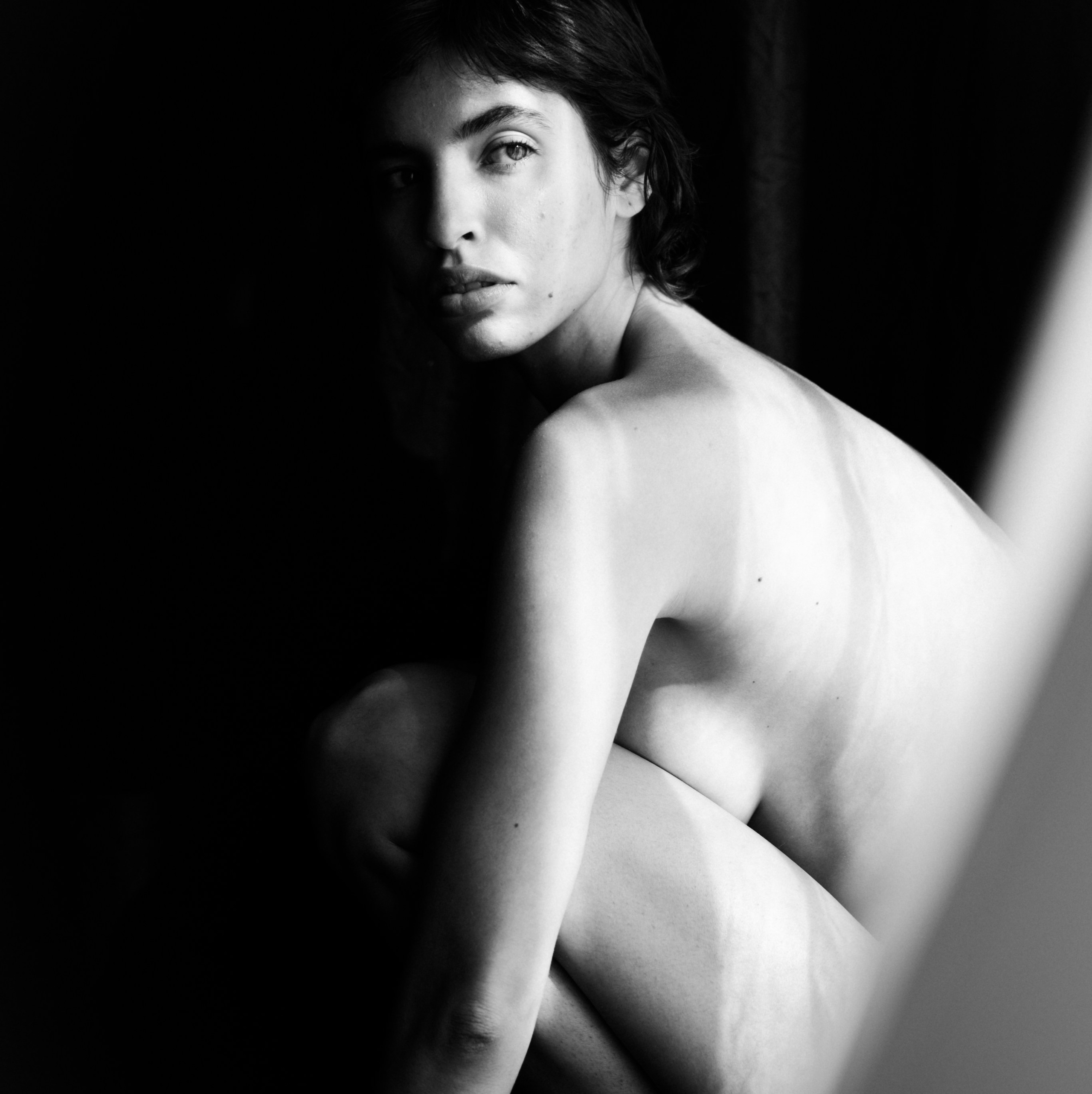 Empowering boudoir photography London — black and white studio portrait, woman in fabrics, artistic implied nude