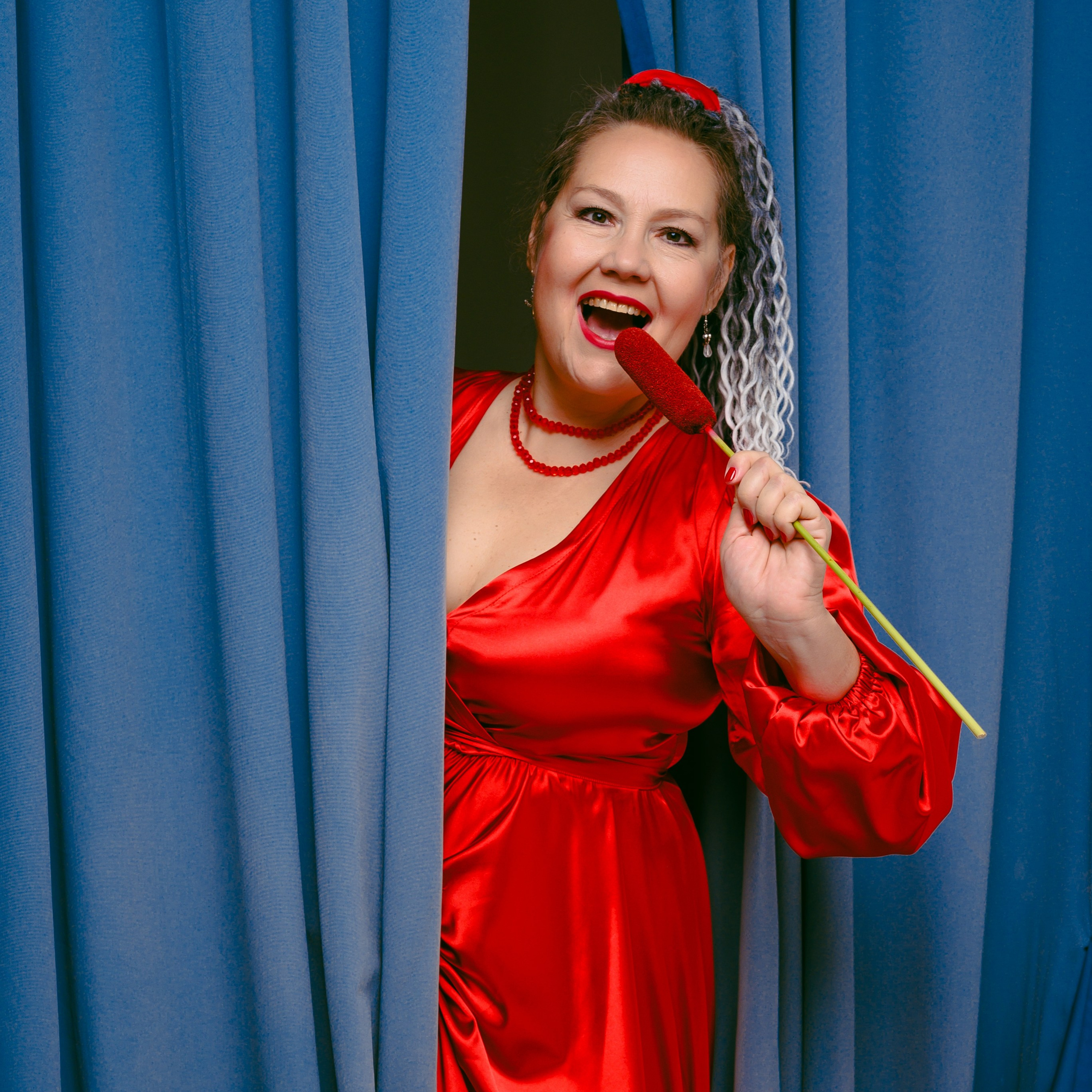 женщина выглядывает из-за кулис и поет в микрофон из камыша