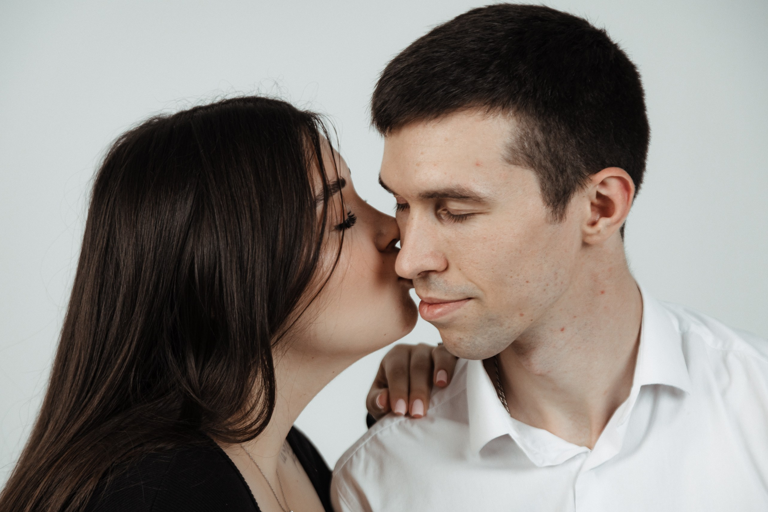 Женщина целует мужчину в щёку, интимный портрет вдвоём.