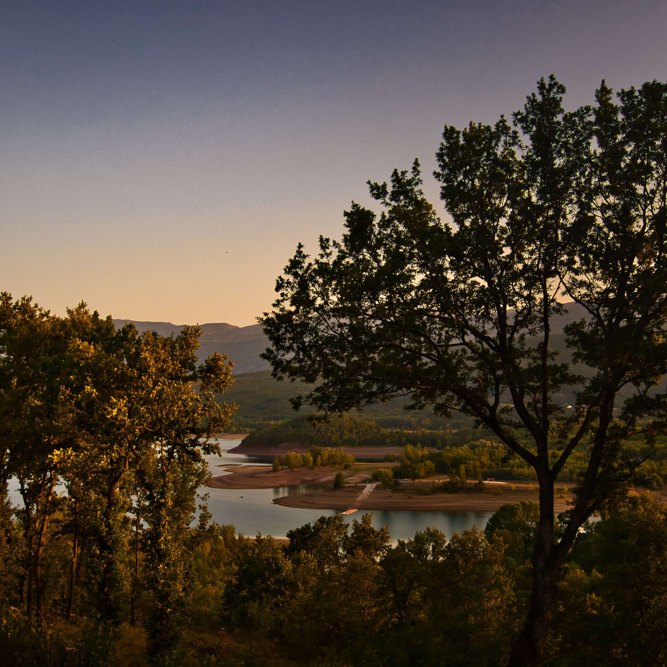Вид на водохранилище Крушчица сквозь деревья на закате, Хорватия