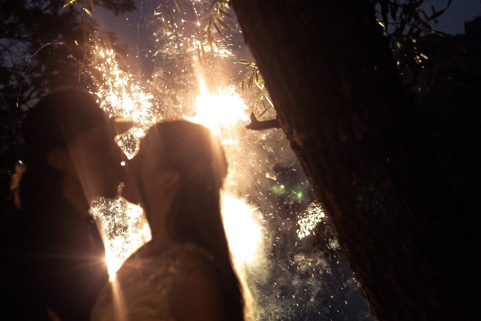 Силуэт целующейся пары на фоне ярких ночных фейерверков