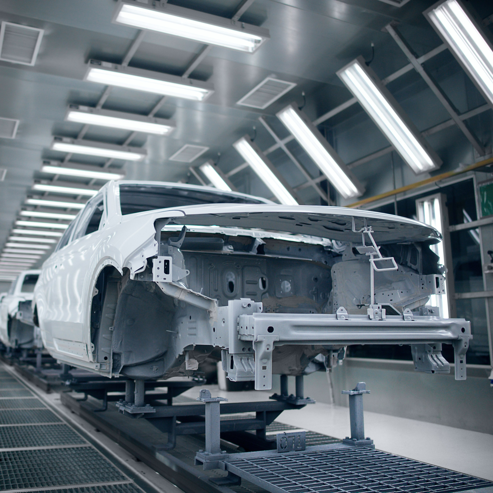 Производственная линия автомобилей в заводском цехе с ярким освещением.