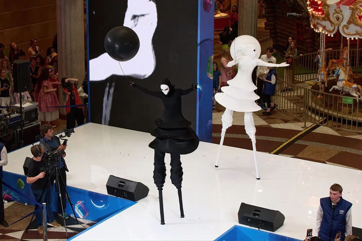 Ходулисты в чёрном и белом образе танцуют на подиуме.