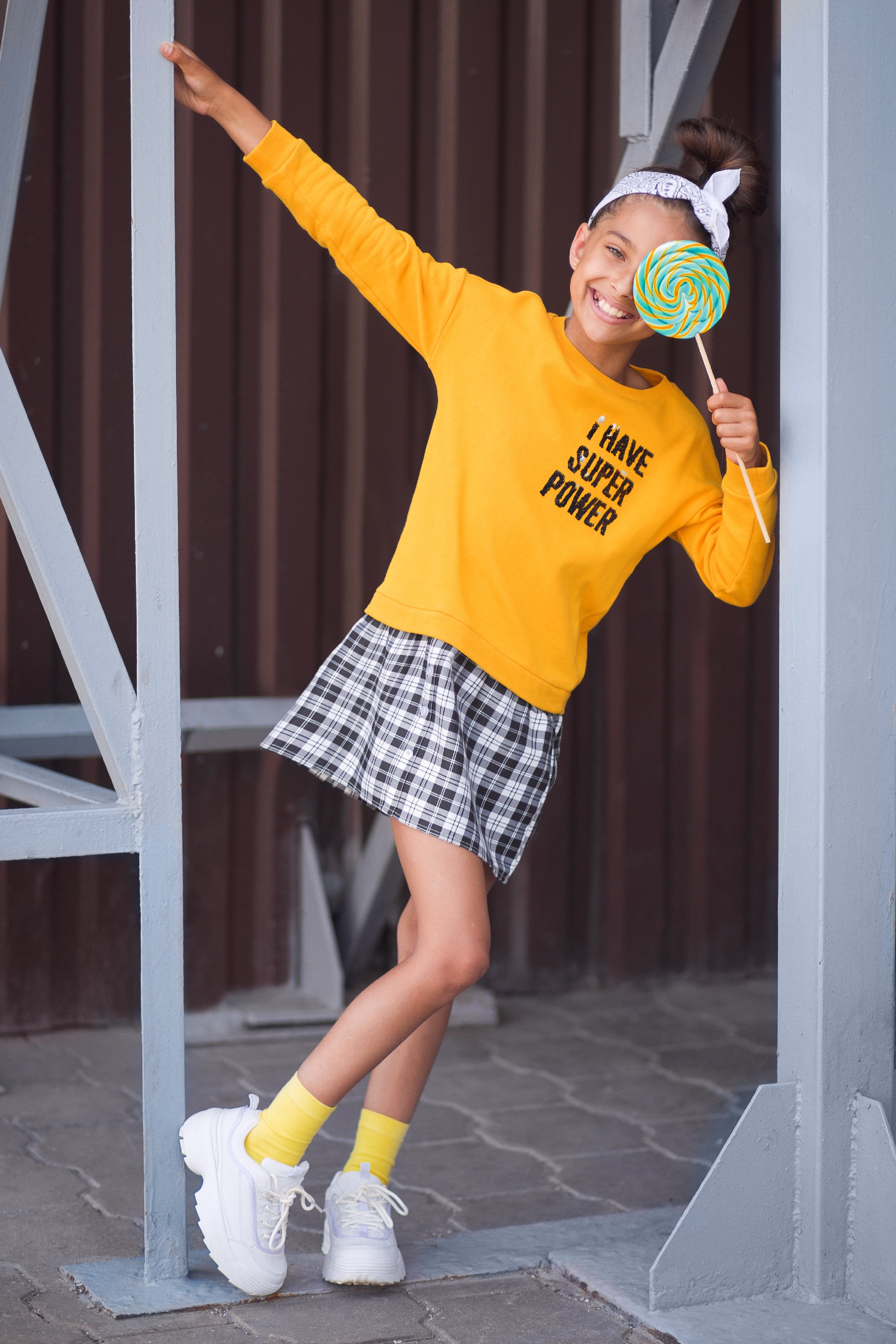 Детская уличная фотосессия в Минске — девочка в желтом свитшоте с леденцом, детская фотография на прогулке