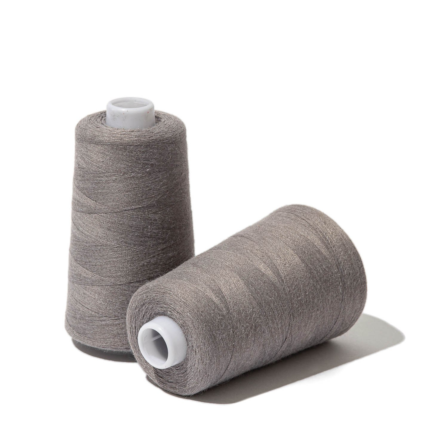 Предметное фото двух катушек серых швейных ниток на белом фоне