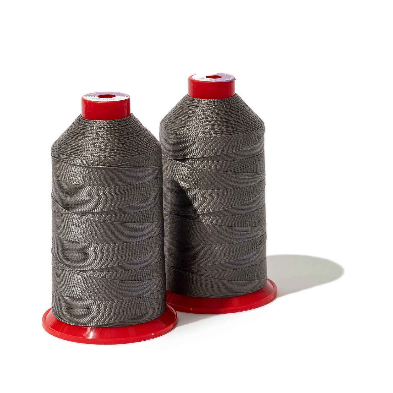 Две катушки тёмно-серых ниток на красных катушечницах на белом фоне