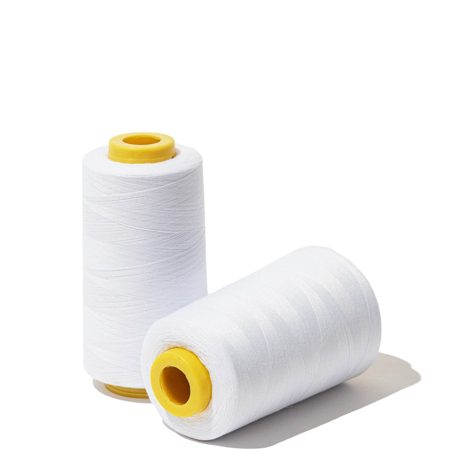 Предметное фото двух катушек белых швейных ниток на белом фоне