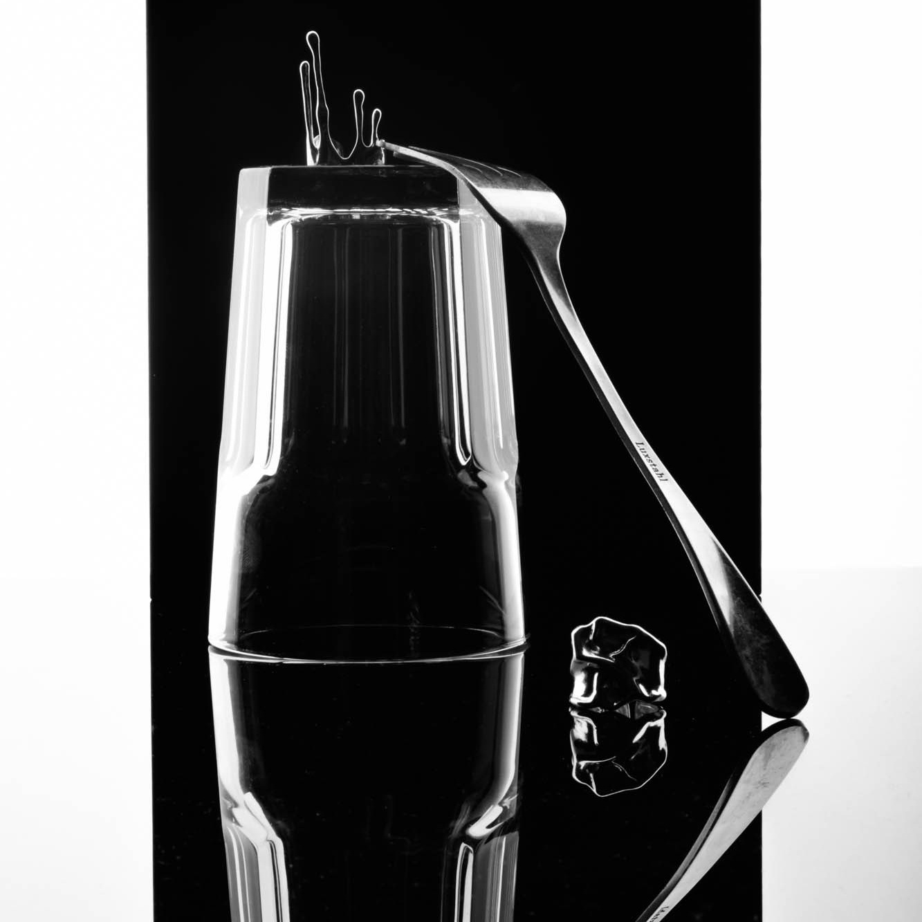 Снимок, на котором изображены стакан, вилка и кольцо, расположенные на поверхности зеркала