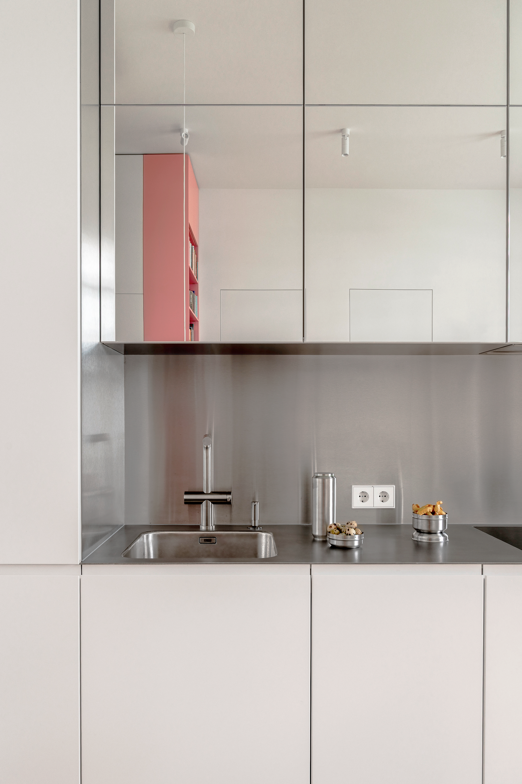 Light kitchen with a metal backsplash and pink shelving
