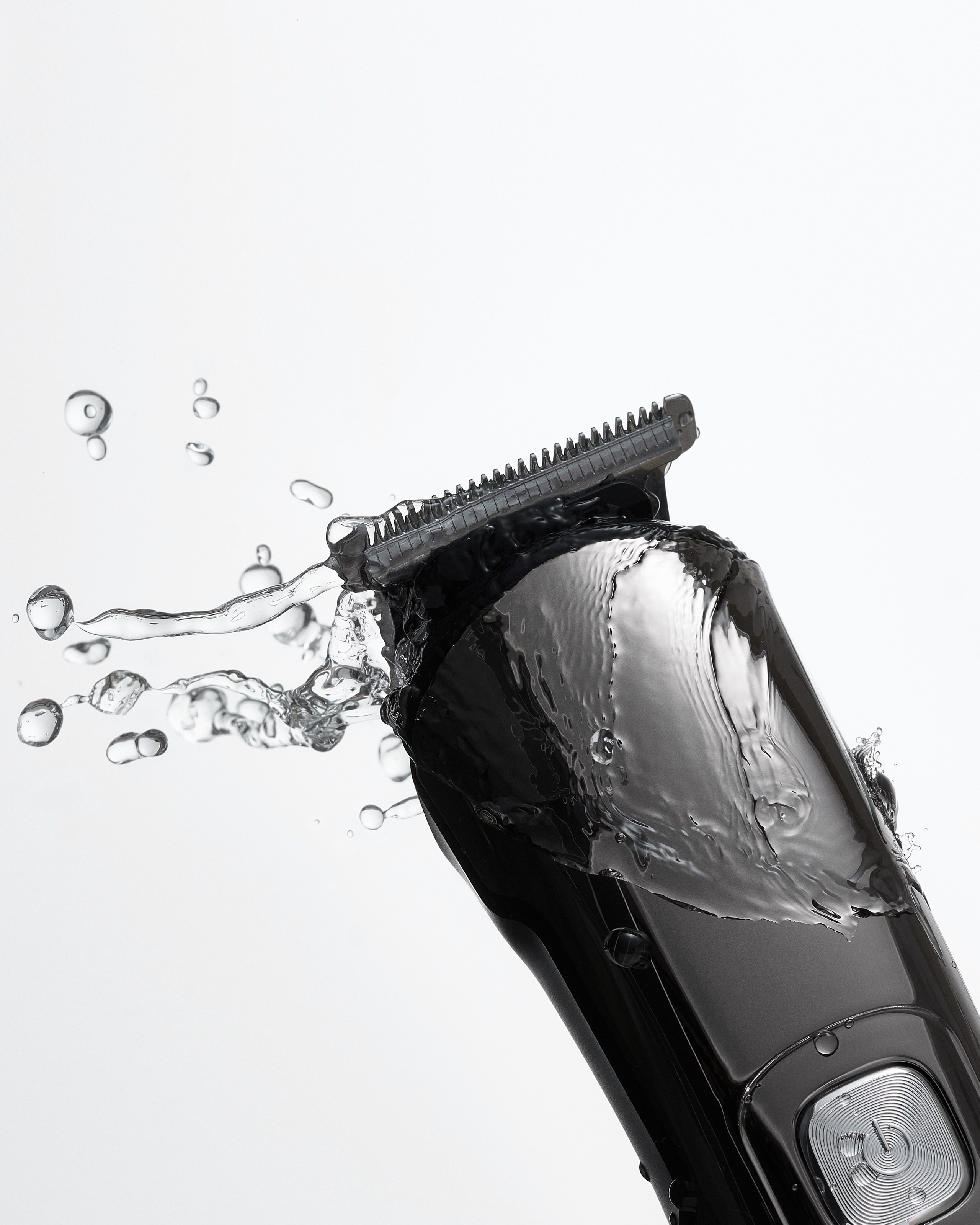 Бритва в брызгах и каплях воды на светлом фоне