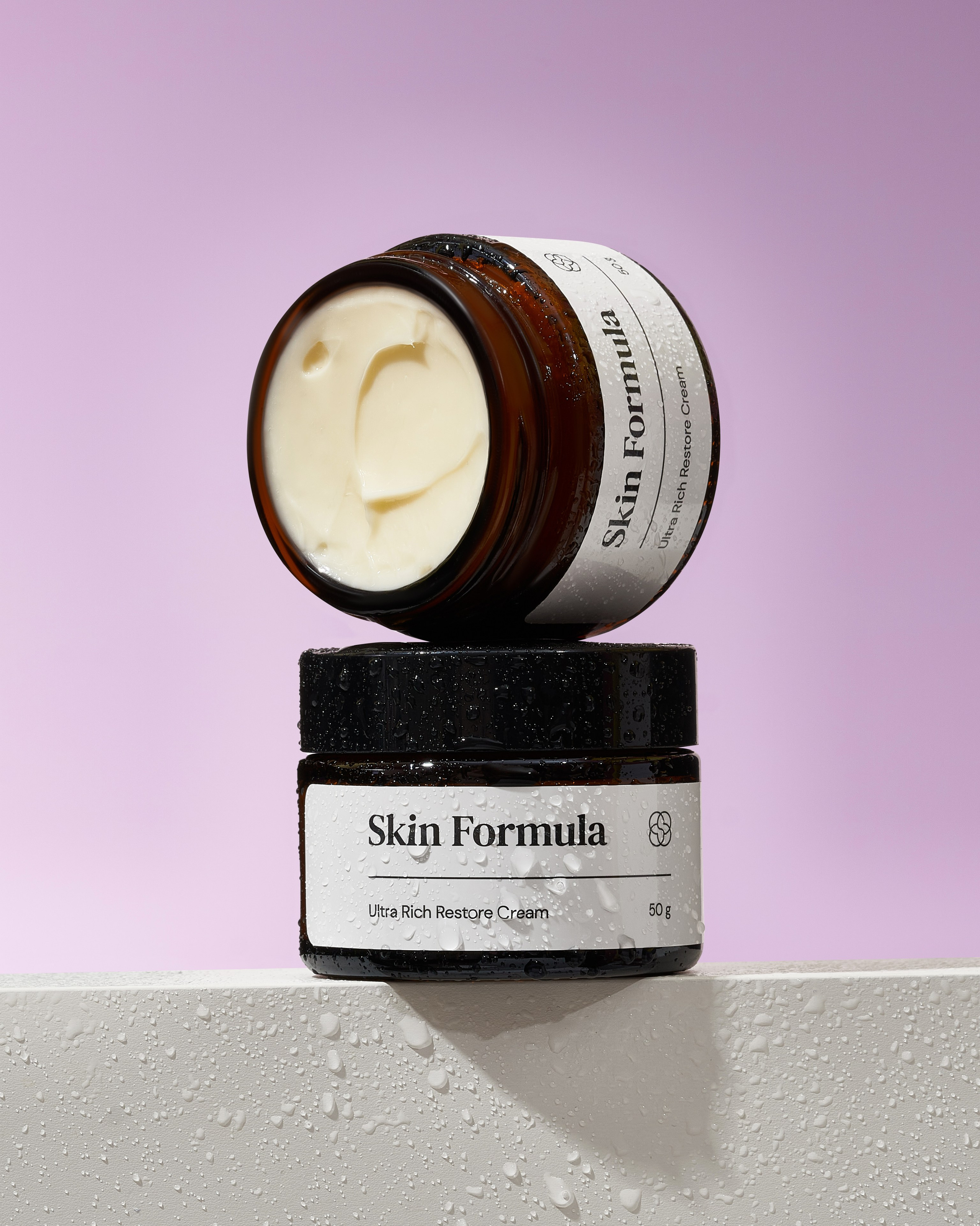 Открытый крем стоит на закрытой банке крема, покрытой каплями воды