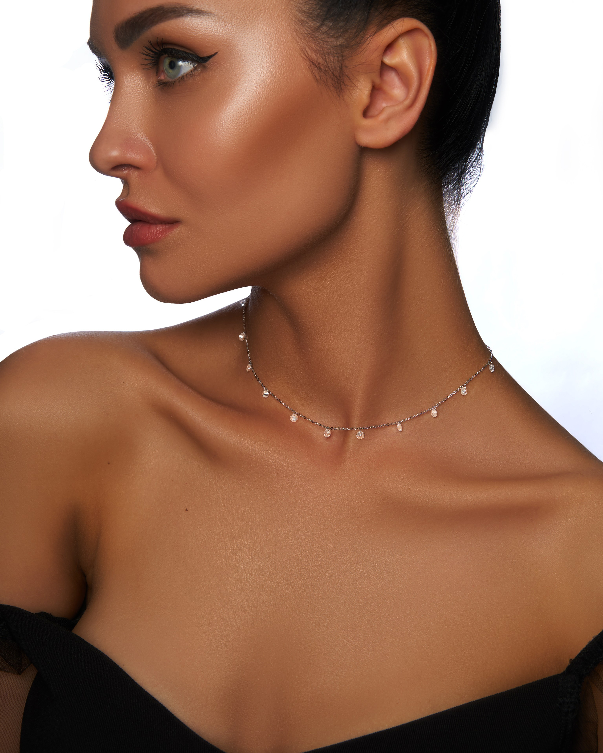 Загорелая модель девушка с ожерельем на шее смотрит в сторону